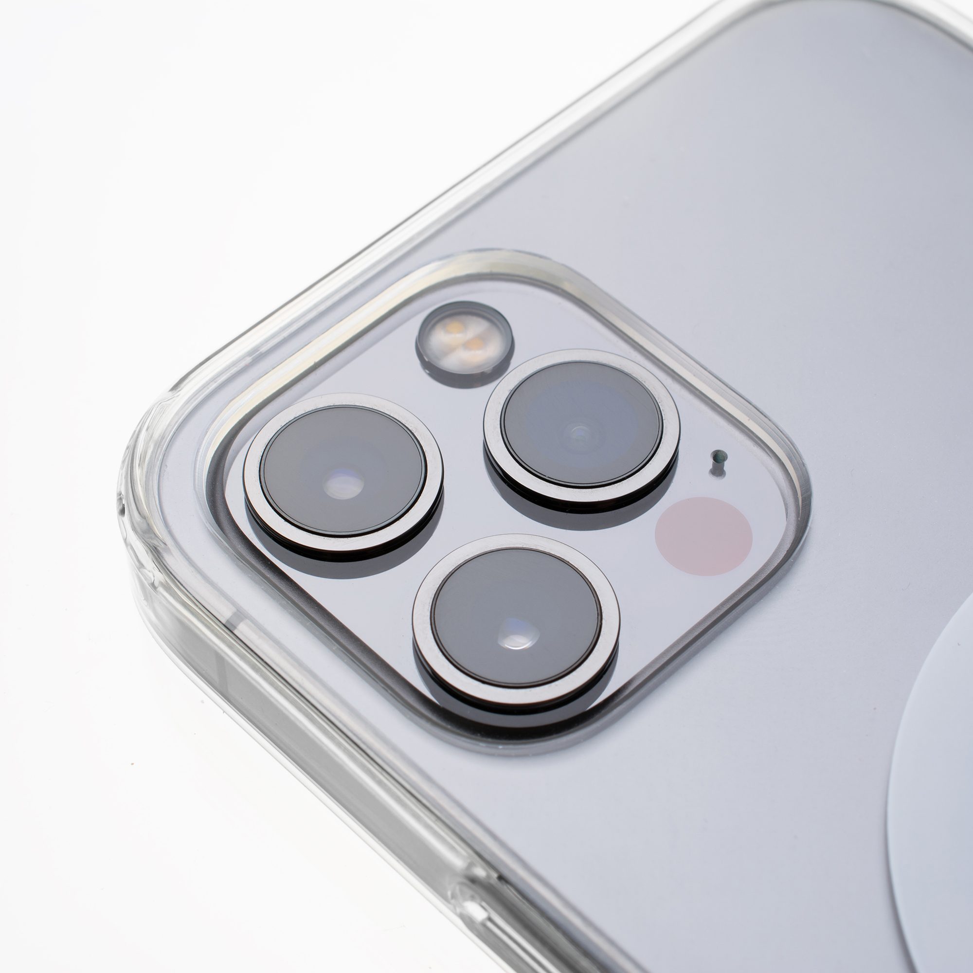 Nahaufnahme der Kameraanordnung eines Smartphones. Drei Objektive, ein Blitz und ein rosa Kreis sind sichtbar. Das Telefon befindet sich in einer durchsichtigen Hülle.
