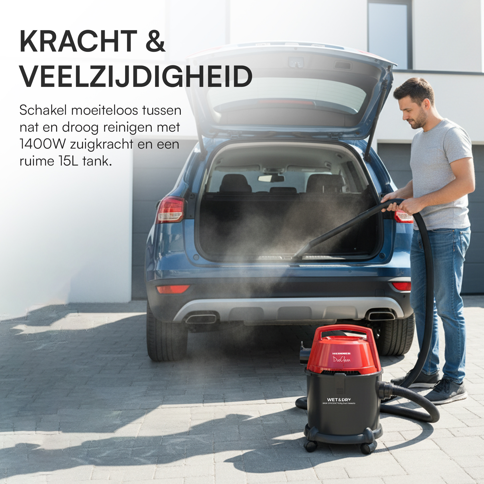 Ein Mann saugt den Kofferraum eines Autos mit einem rot-schwarzen Staubsauger. Das Auto ist blau, der Hintergrund ist ein Haus.