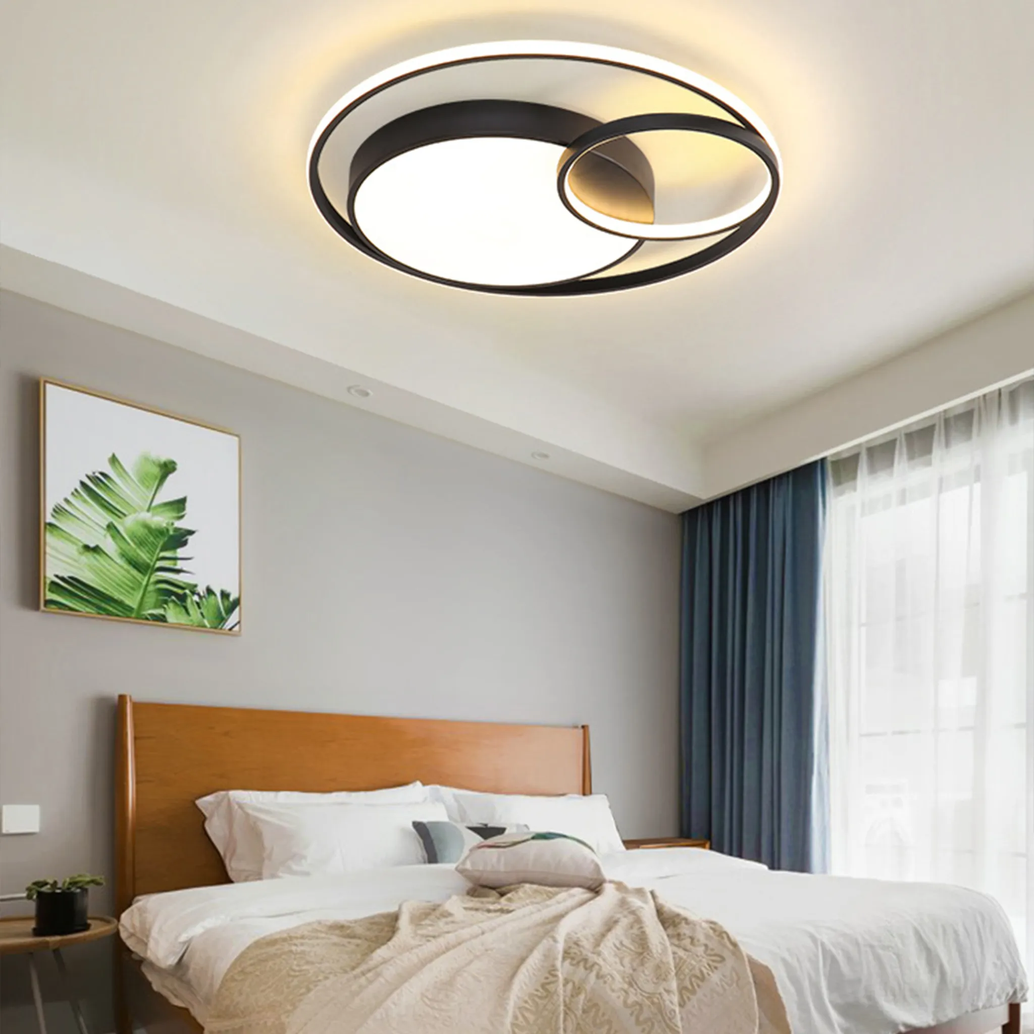 Schlafzimmer mit moderner Deckenleuchte. Ein Bett steht im Zentrum mit einem Bild an der Wand und Vorhängen.
