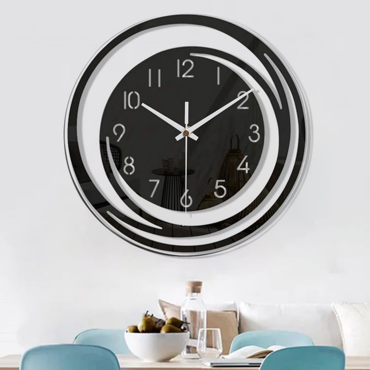 Eine moderne Wanduhr mit schwarz-weißem Kreisdesign. Die Zeiger der Uhr zeigen auf zehn nach eins. Darunter steht ein Esstisch.