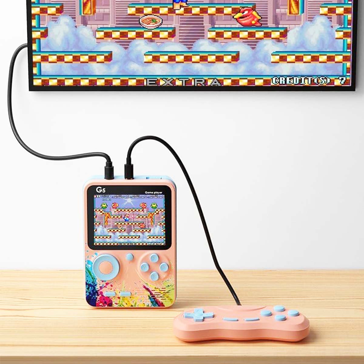 Una consola de juegos portátil conectada a un televisor. La consola muestra un juego retro. Un controlador separado está sobre la mesa.