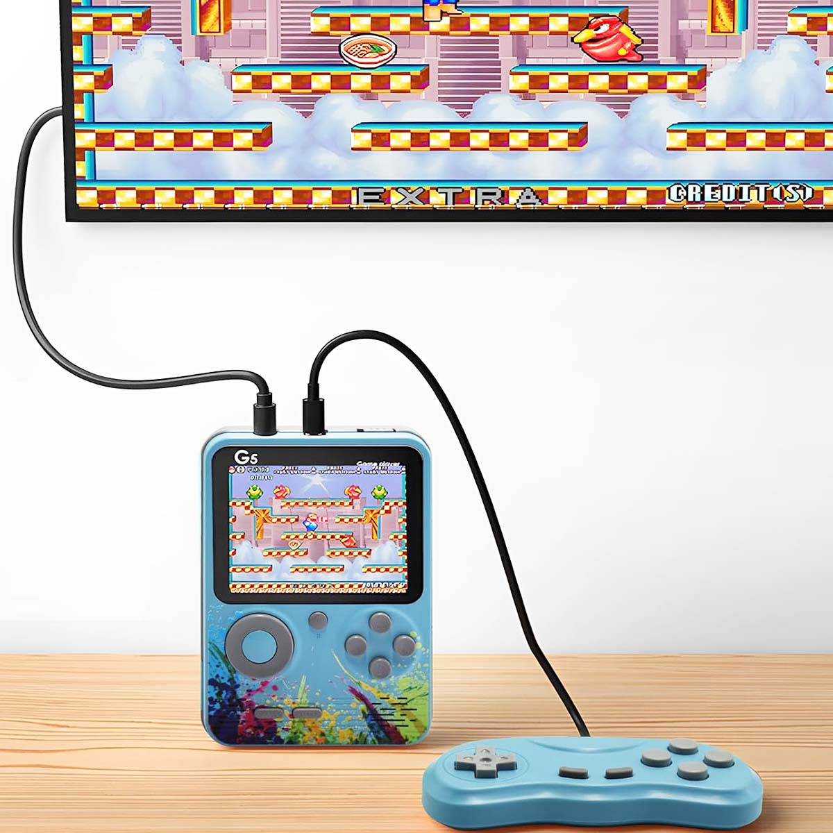 Una consola de juegos portátil está conectada a un televisor. La consola muestra un juego retro. Un controlador descansa sobre madera.