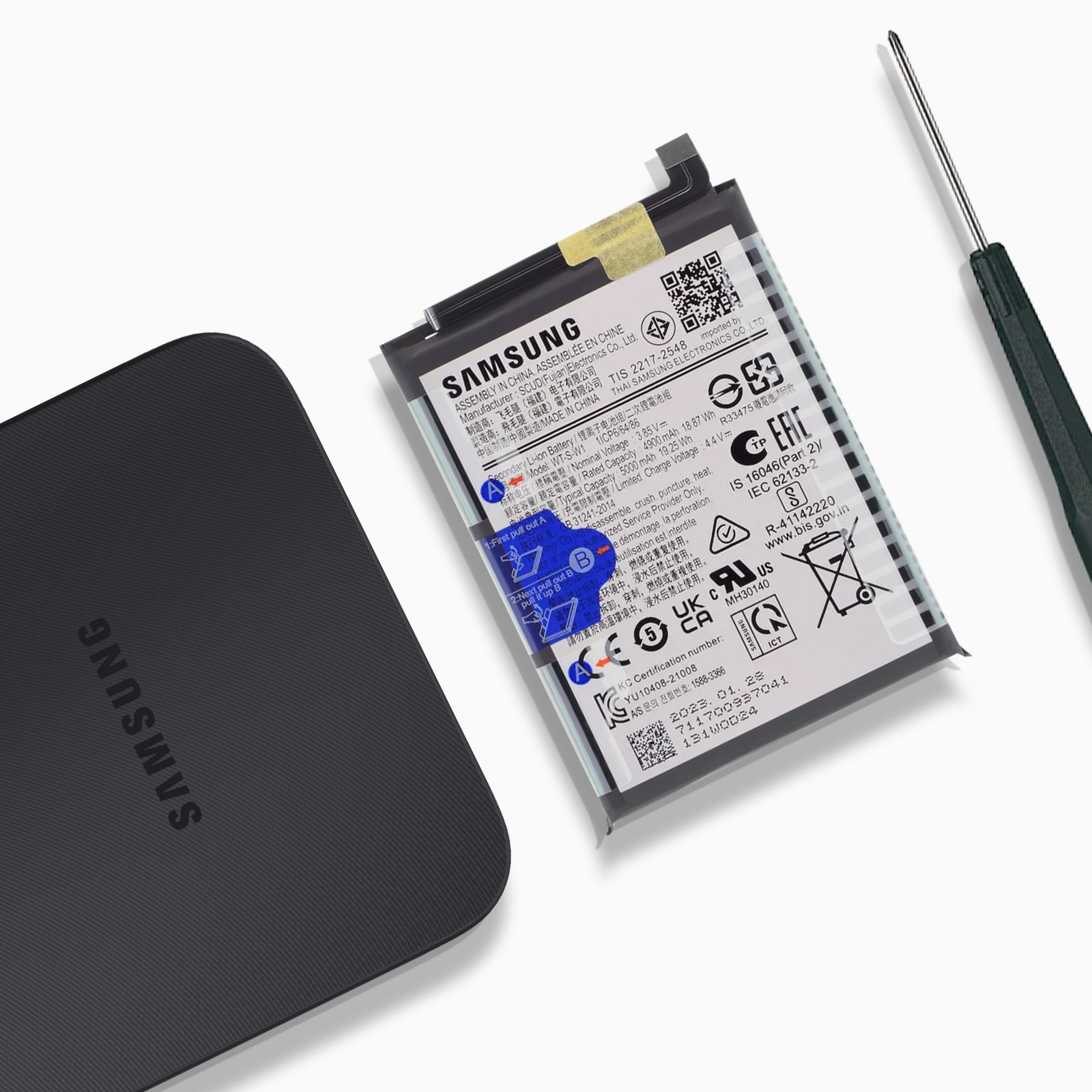 Ein Samsung-Telefonakku mit Text, ein schwarzes Ladepad und ein Schraubendreher.
