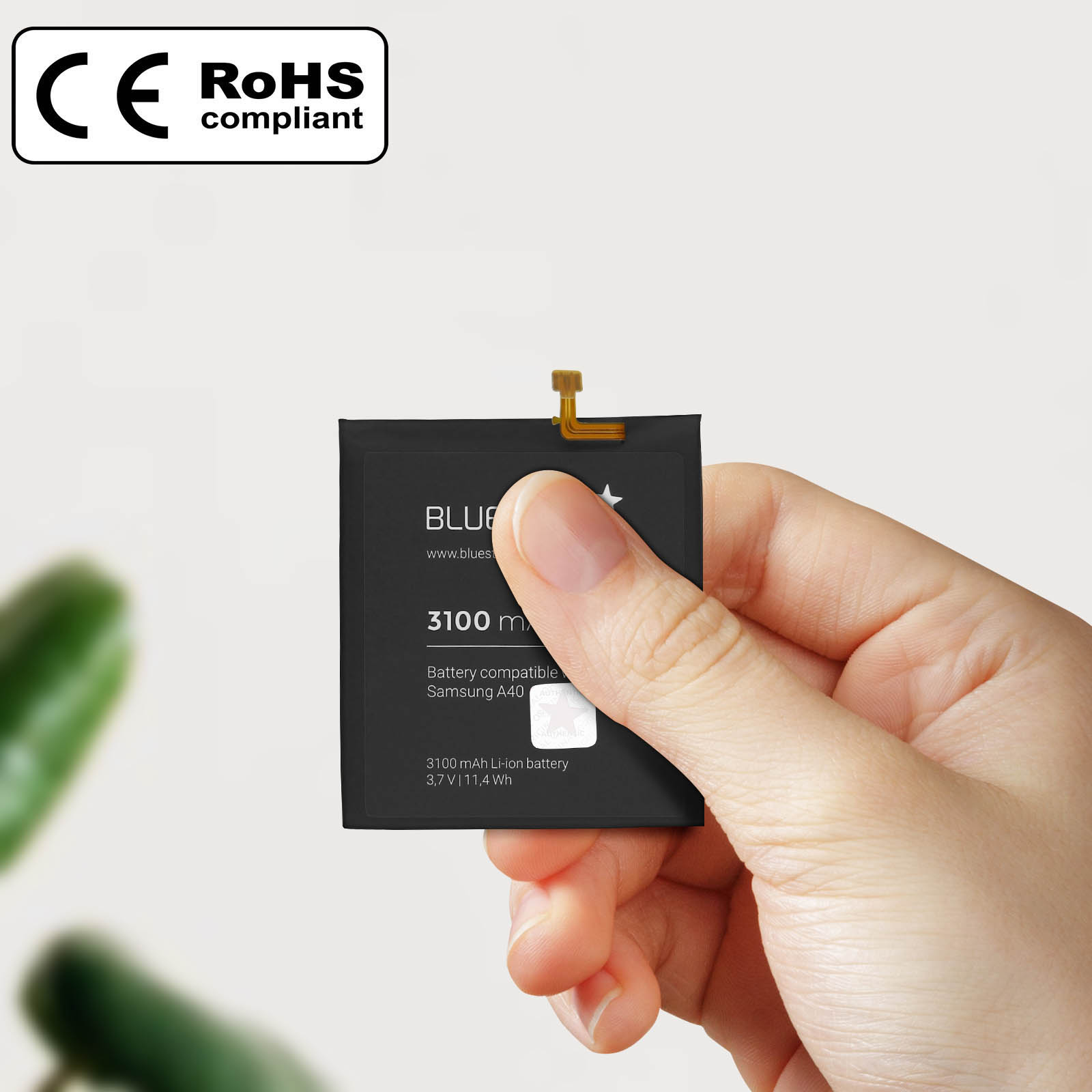 Una mano che tiene una batteria del telefono nera. La batteria ha testo bianco e un connettore dorato.
