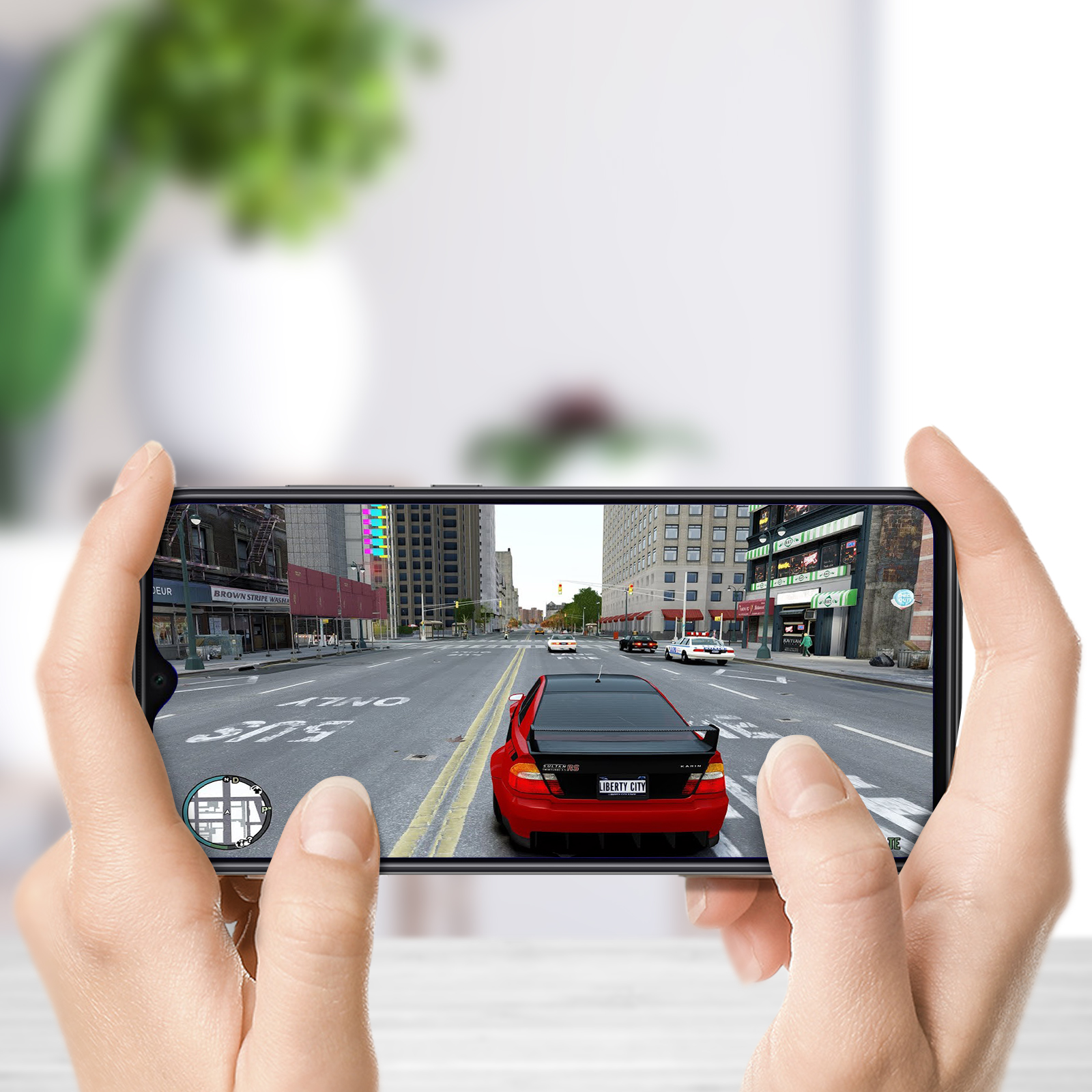 Mani che tengono un telefono, che mostra una scena di gioco con un'auto rossa che guida in città.