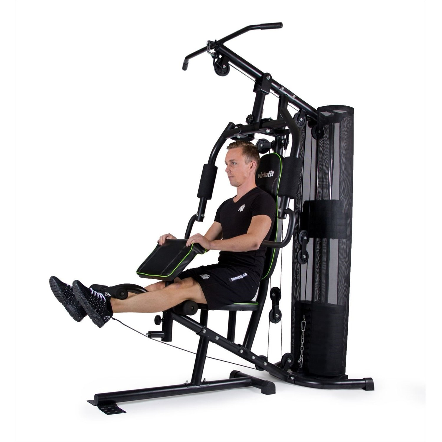 Mann in schwarzer Sportkleidung benutzt eine schwarz-grüne Trainingsmaschine. Das Fitnessstudio hat Gewichte und verschiedene Griffe und Stützen.