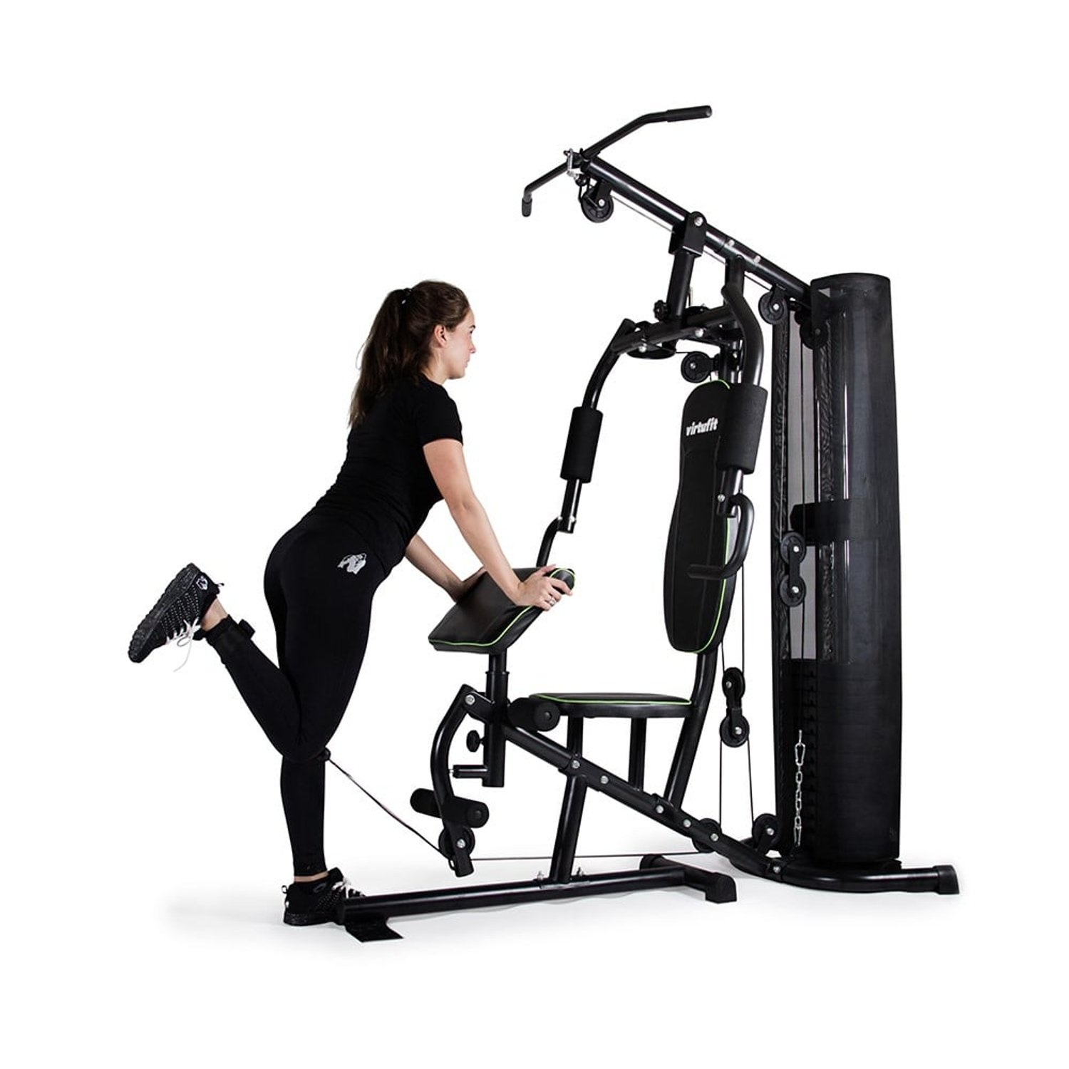 Eine Frau in schwarzer Sportkleidung trainiert an einer schwarzen Fitnessmaschine. Sie hebt ihr Bein. Die Maschine hat Gewichte und Stangen.