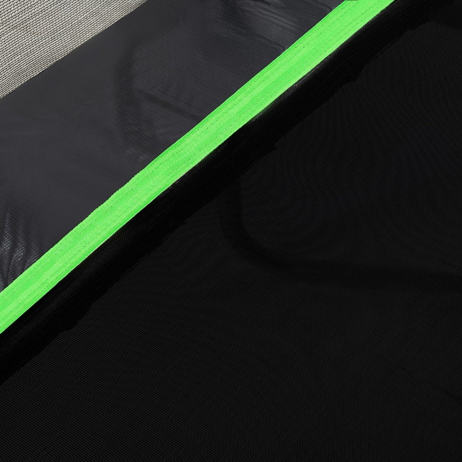 Nahaufnahme eines schwarzen Stoffes mit einem hellgrünen Streifen entlang einer diagonalen Naht. Der Hintergrund ist ein Netzmaterial.