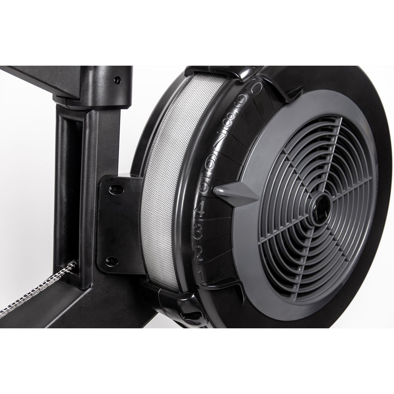 Nahaufnahme des Schwungrads eines Rudergeräts. Der Ventilator ist schwarz und grau, mit Zahlen. Eine silberne Kette ist sichtbar, der Hintergrund ist weiß.