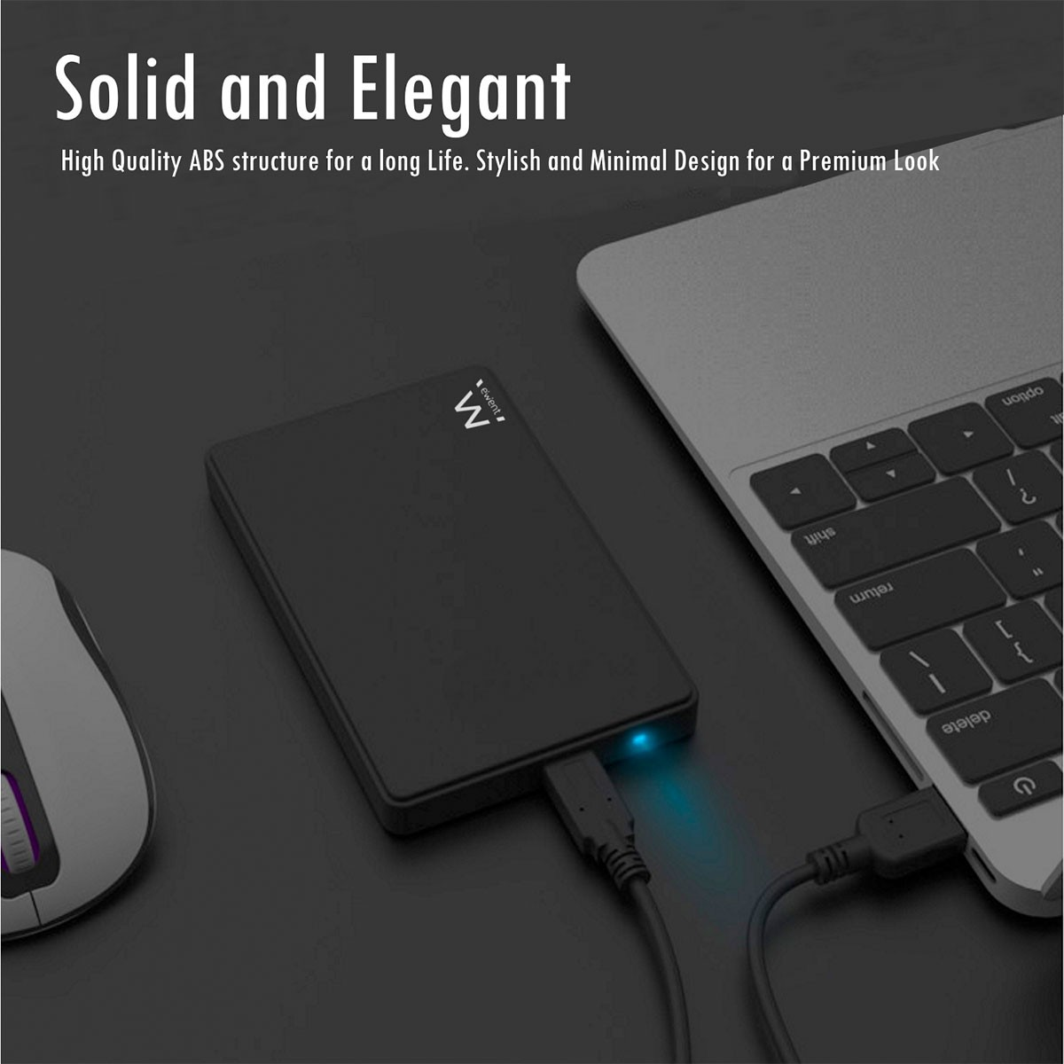 Un disco rigido esterno nero è collegato a un laptop. Un mouse è a sinistra. Lo sfondo è scuro.