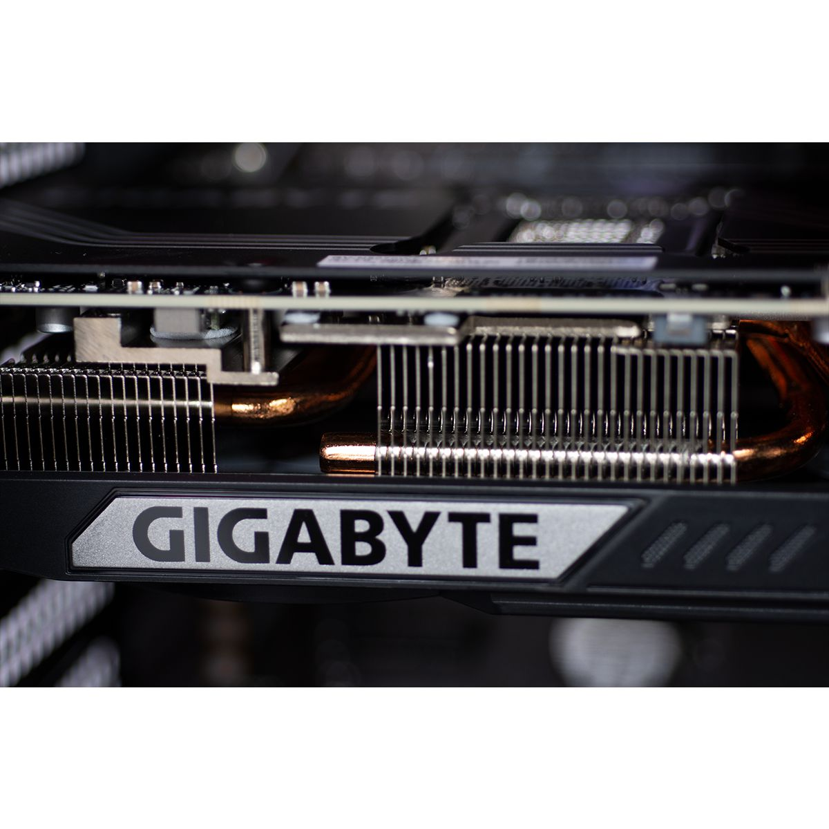 Close-up van een Gigabyte grafische kaart. Zilver en zwart ontwerp. Koperen buizen en koellichamen zijn zichtbaar. De achtergrond is donker.