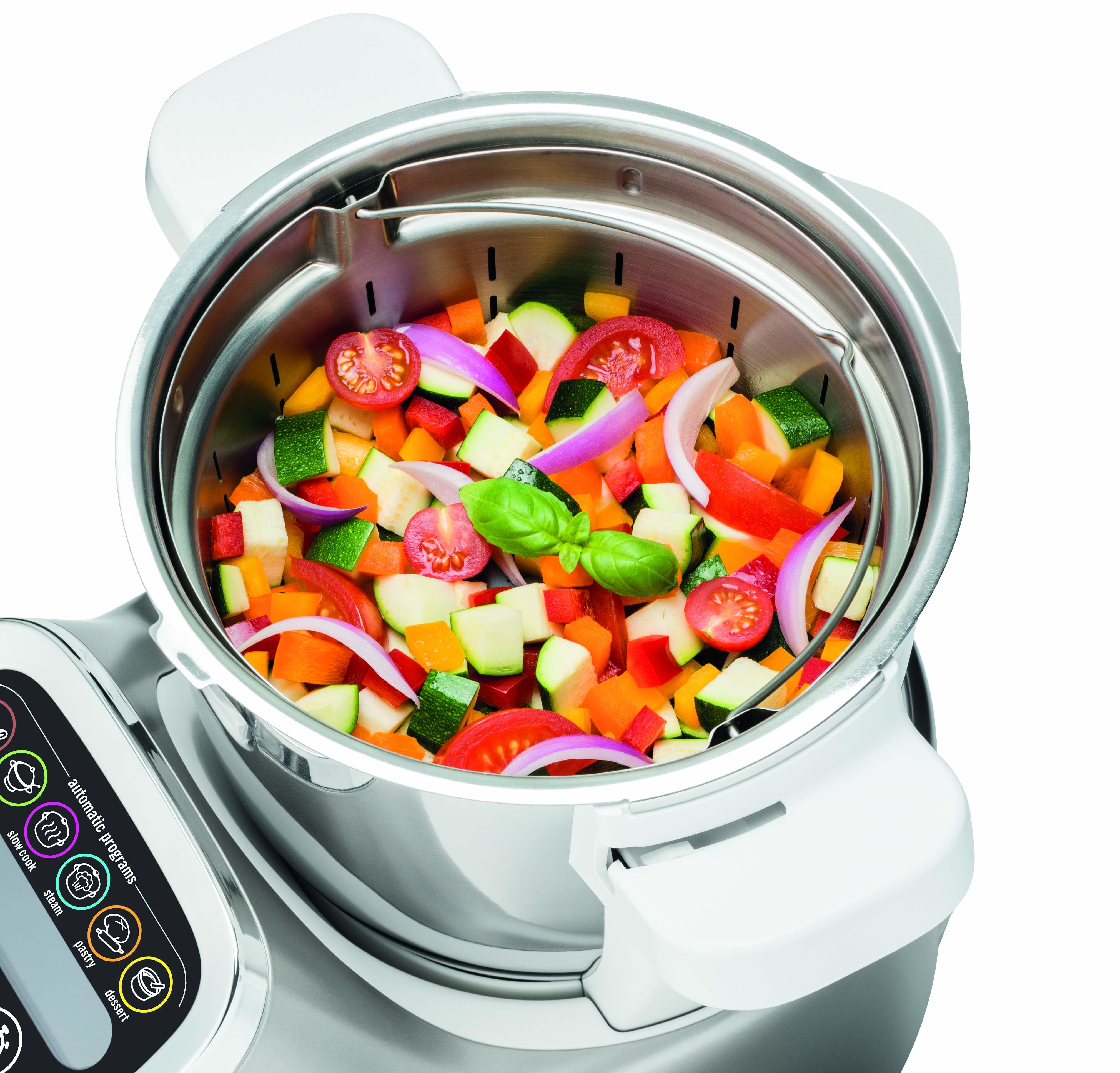 Un robot culinaire avec des légumes hachés à l'intérieur. Des légumes rouges, oranges, verts et violets sont visibles.