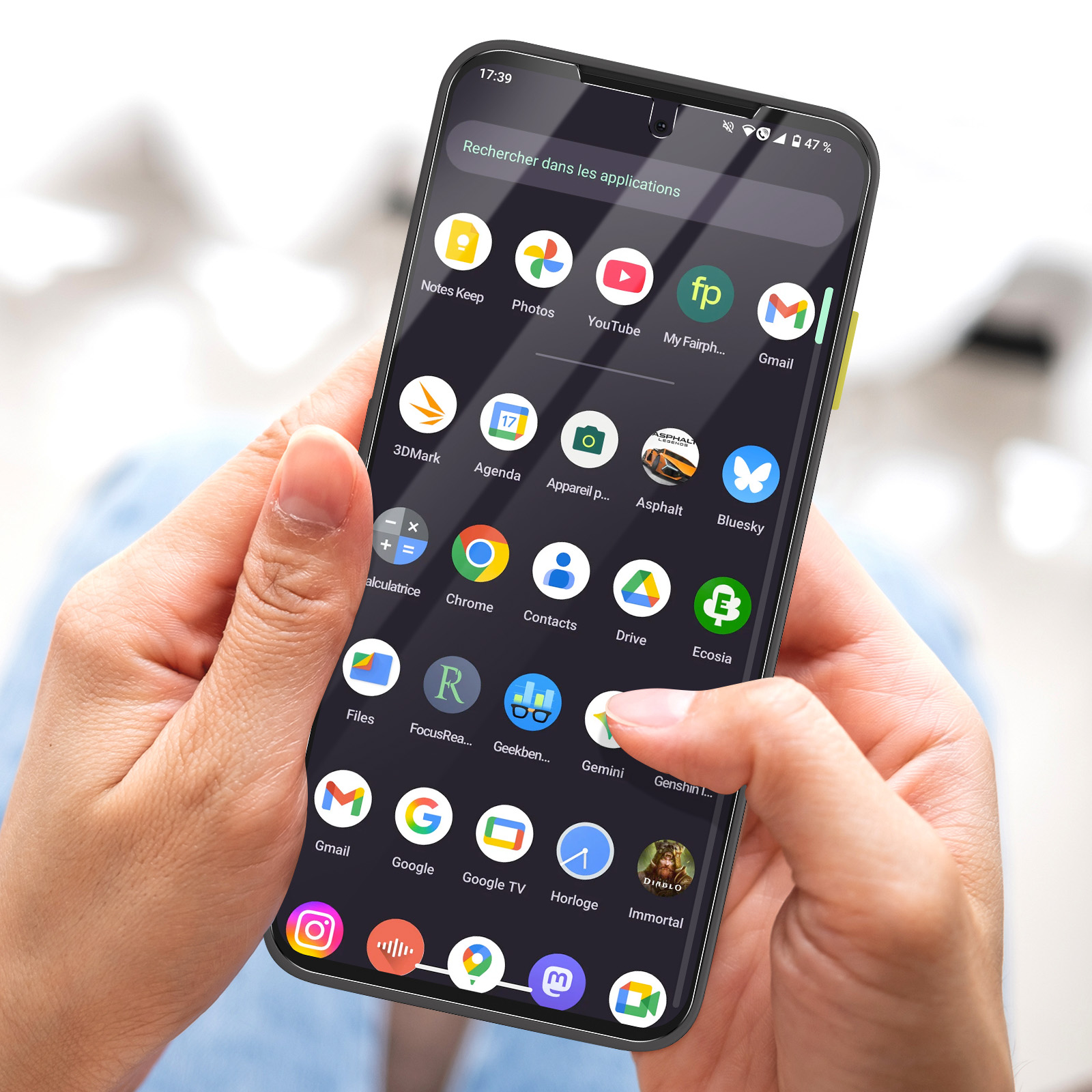 Una mano tiene uno smartphone che mostra icone di app. L'app Gemini viene toccata. Lo schermo mostra l'ora e la batteria.