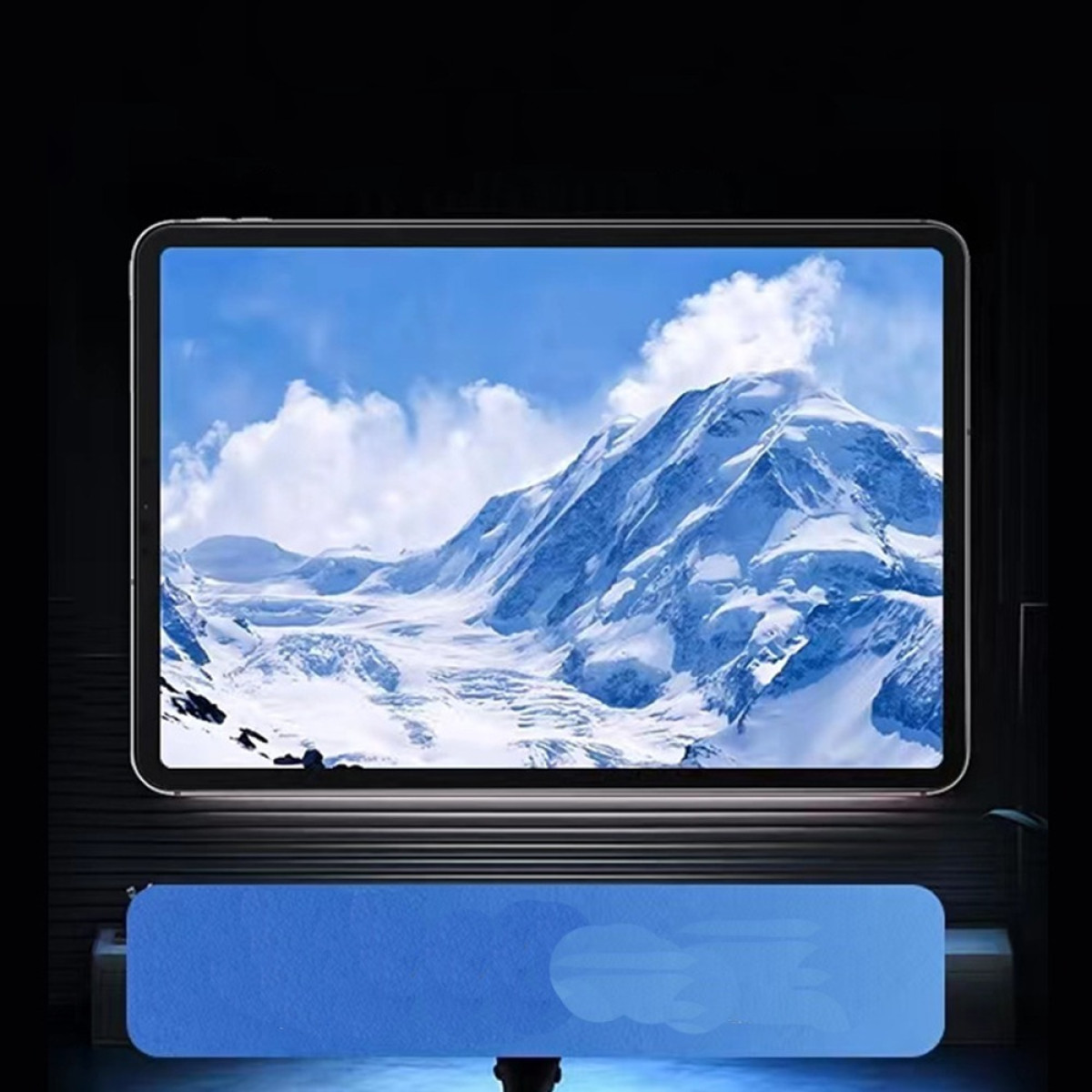 Tablet toont besneeuwde bergen onder een blauwe lucht. Een blauwe rechthoek onderaan, en de achtergrond is donker.