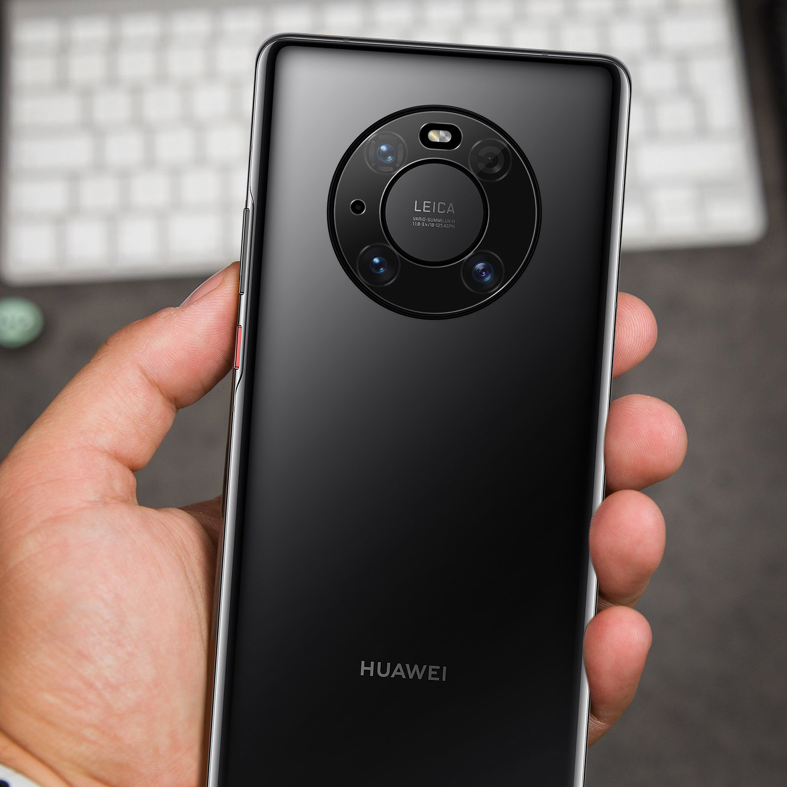 Una mano che tiene un telefono Huawei nero. La fotocamera Leica è visibile e il retro del telefono è lucido.
