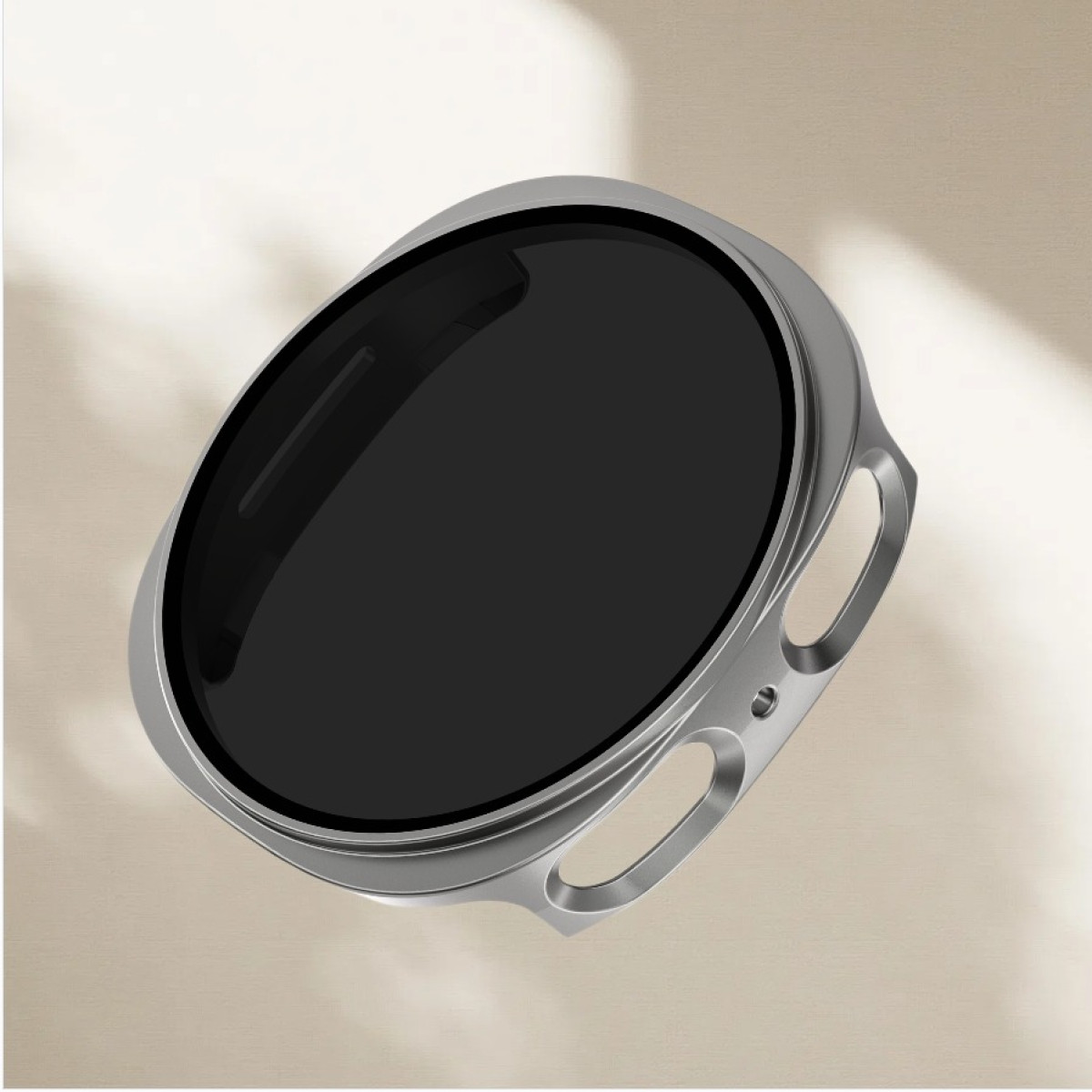 Un primo piano di un filtro per obiettivo argentato con vetro nero. Lo sfondo è una superficie beige con ombre morbide.