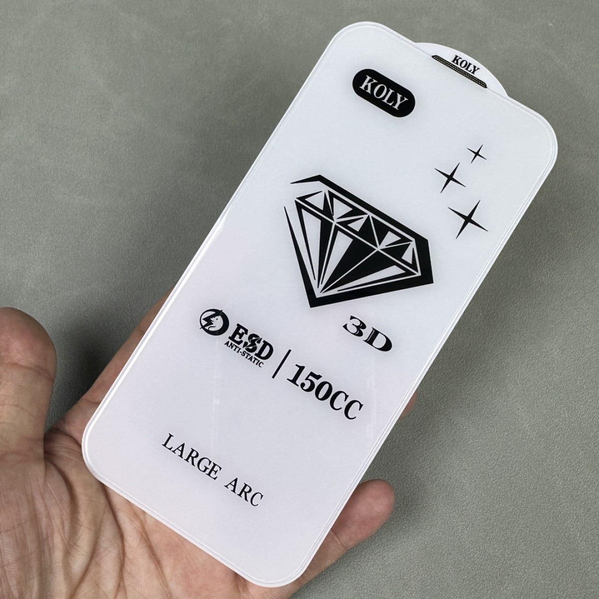 Una mano tiene una protezione per schermo bianca. Ha una grafica a diamante e testo, tra cui 'KOLY', '3D' e 'LARGE ARC'.