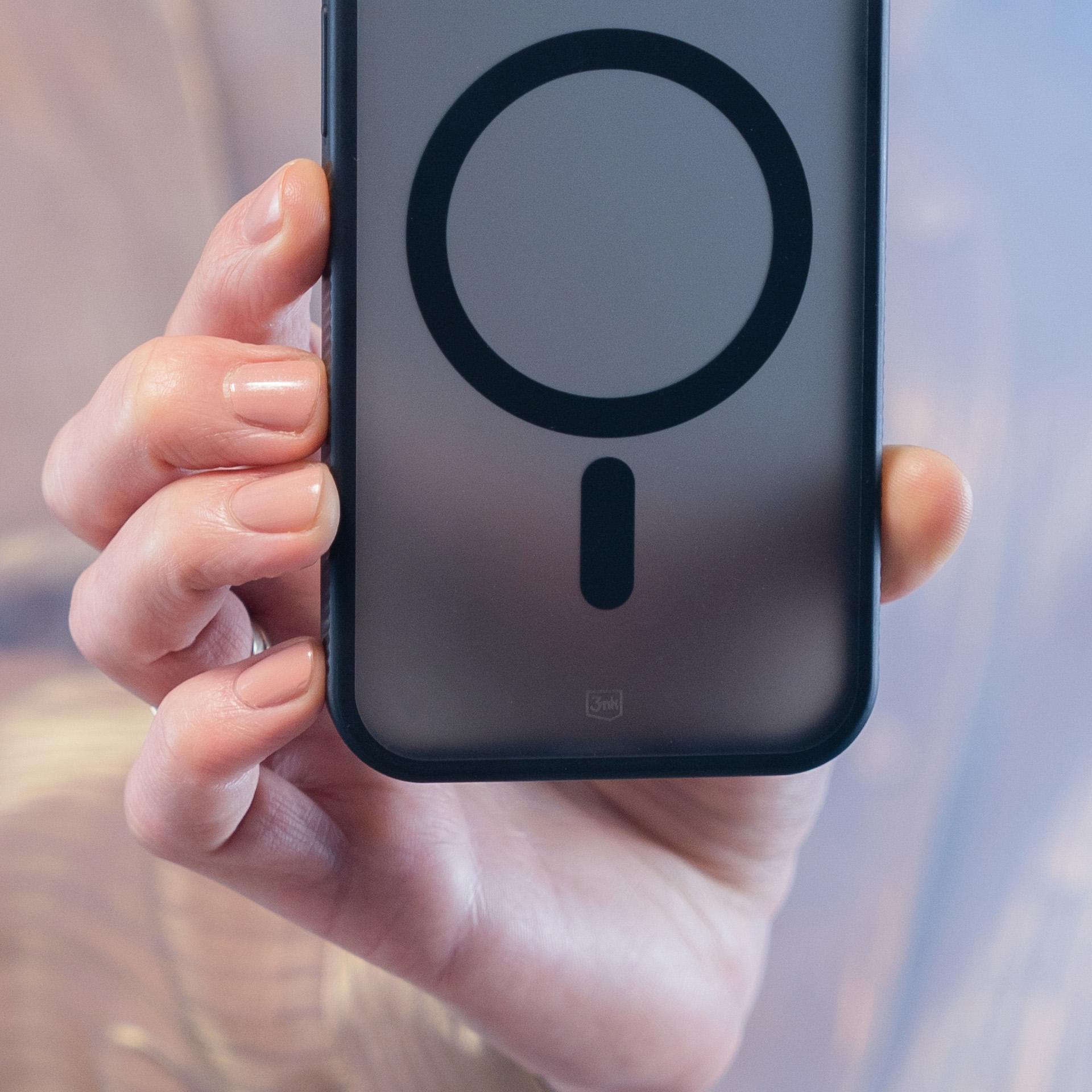 Dłoń trzyma etui na telefon z czarnym okręgiem i prostokątem. Paznokcie pomalowane na jasnoróżowo.