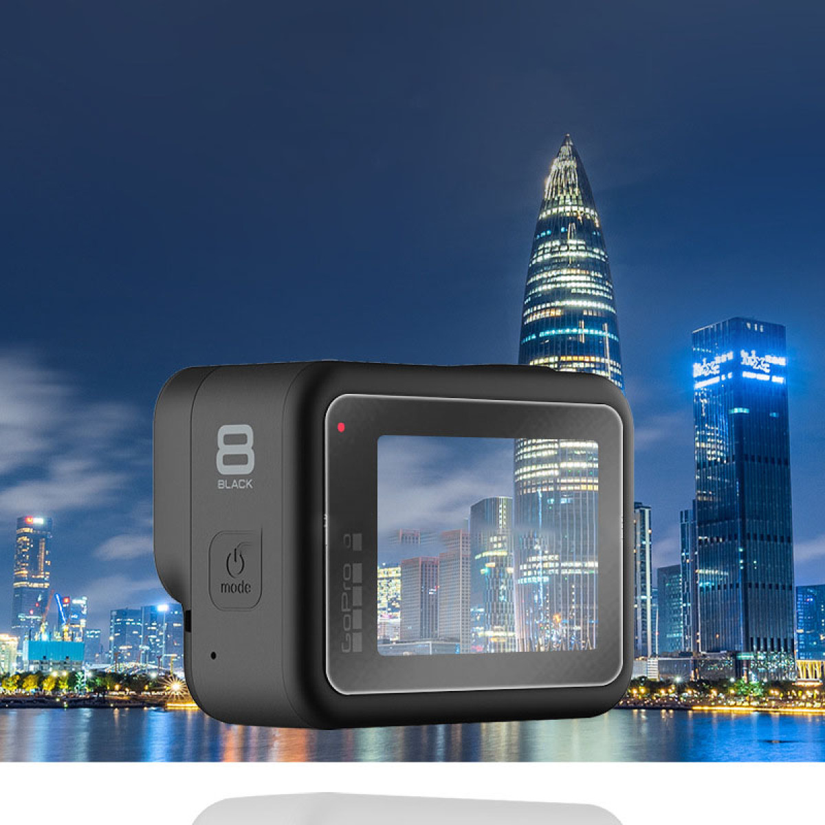 Una fotocamera GoPro 8 nera in primo piano, con uno skyline notturno sullo sfondo. Edifici e luci visibili.