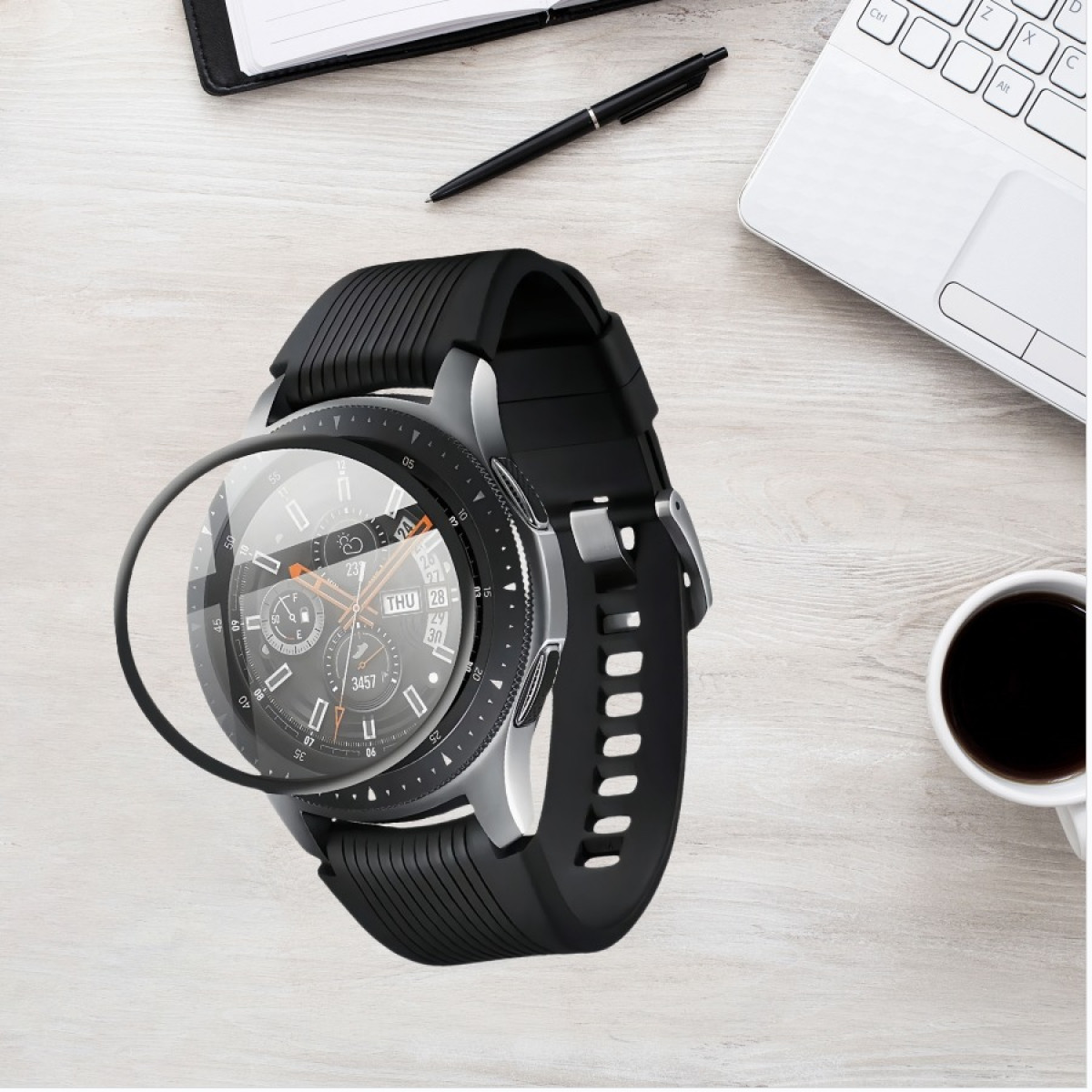 Uno smartwatch con cinturino nero è su una scrivania di legno con penna, taccuino, laptop e tazza di caffè.