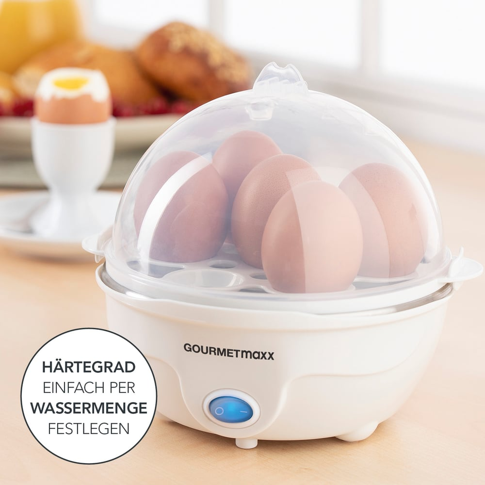 Un cuocitore per uova con uova all'interno, un uovo sodo in un portauovo e elementi per la colazione sullo sfondo.