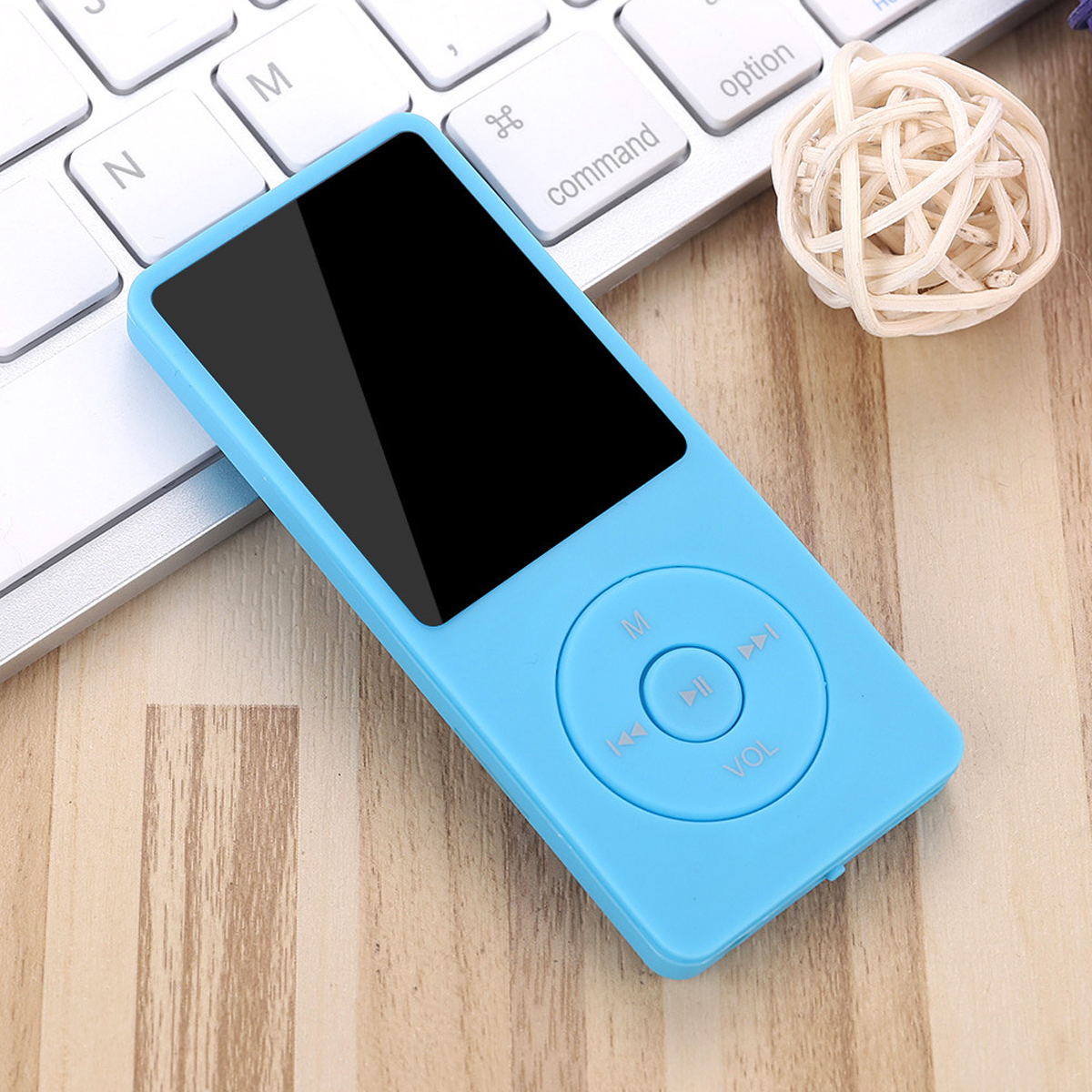 Ein hellblauer MP3-Player mit schwarzem Bildschirm liegt auf einer Tastatur und Holzoberfläche. Daneben liegt ein Korbball.