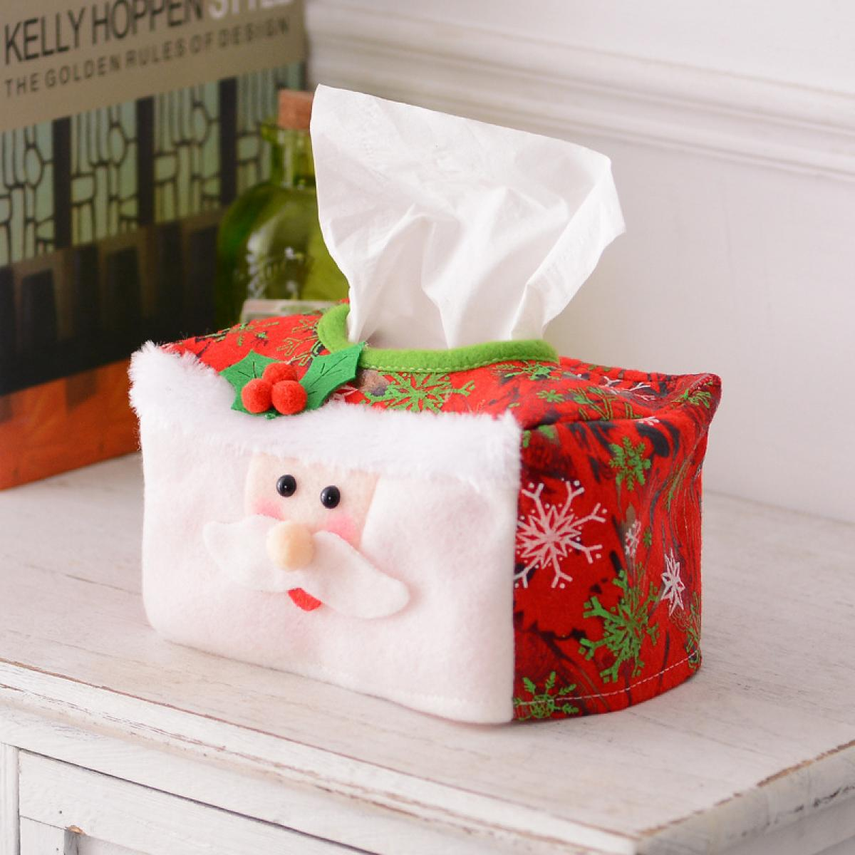 Eine Weihnachtstücherschachtel mit Santa Claus auf einer weißen Oberfläche. Roter Stoff mit Schneeflocken und grünen Akzenten.