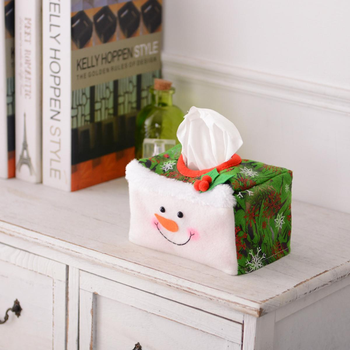 Eine Schneemann-Taschentuchbox auf einer weißen Kommode. Bücher und eine grüne Flasche sind im Hintergrund.