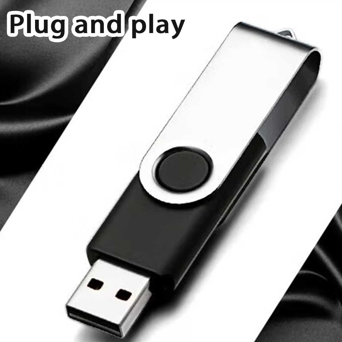 Ein USB-Stick mit schwarzem und silbernem Design liegt auf einer weißen Oberfläche. Der Hintergrund zeigt schwarzen Stoff.