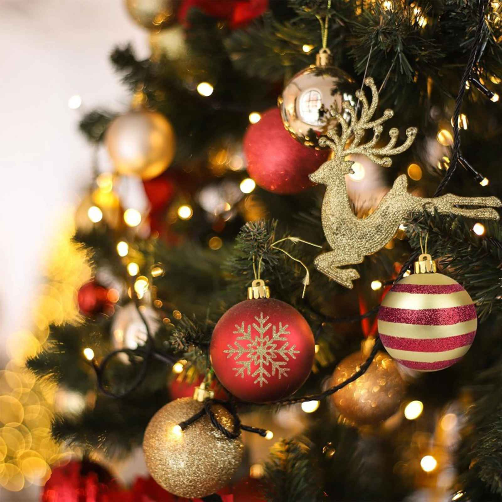 Weihnachtsbaum mit Ornamenten, darunter ein goldener Rentier, rote Schneeflocken- und gestreifte Kugeln, und Lichter.
