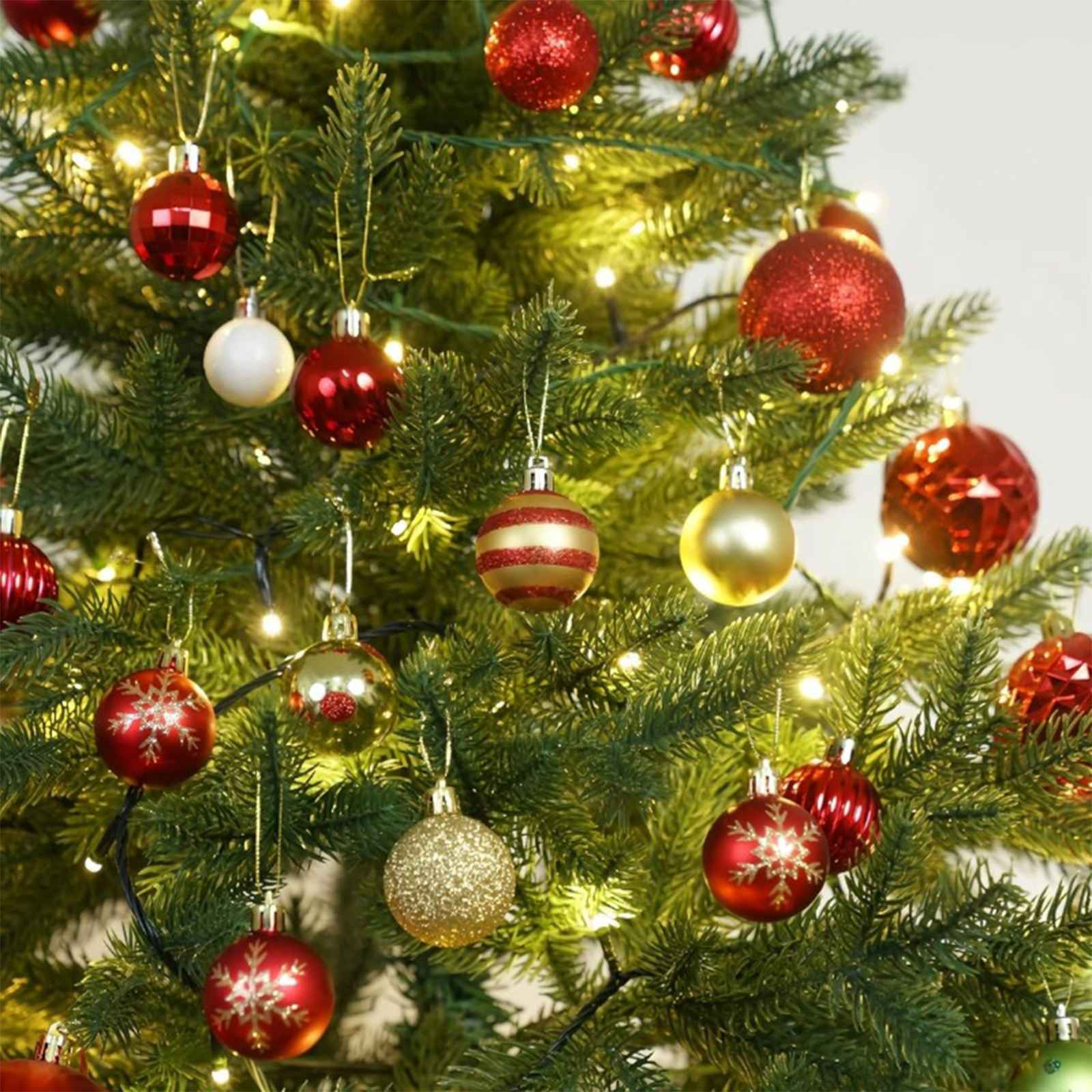 Ein geschmückter Weihnachtsbaum mit roten, goldenen und weißen Ornamenten, funkelnden Lichtern und grünen Nadeln.