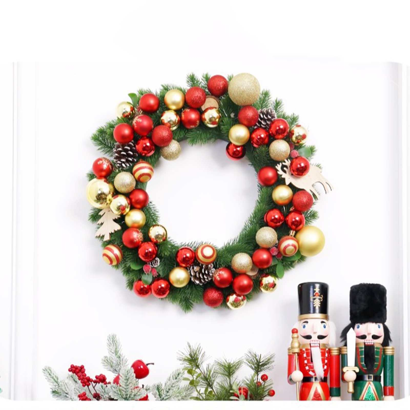 Ein Weihnachtskranz mit roten und goldenen Ornamenten, Tannenzapfen und zwei Nussknackern auf weißem Hintergrund.