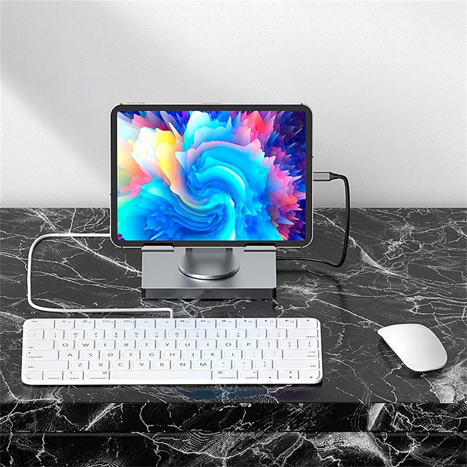 Tablet auf Ständer mit farbenfrohem Bildschirm, Tastatur und Maus auf Marmoroberfläche. Kabel verbinden Geräte.