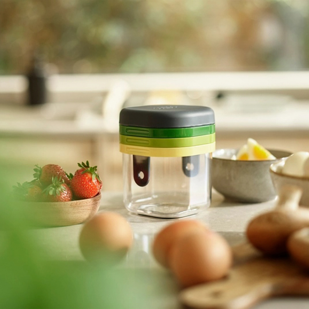 Un robot da cucina con fragole, uova e ciotole di ingredienti. Il robot ha strati neri, verdi e gialli. Lo sfondo è una cucina.