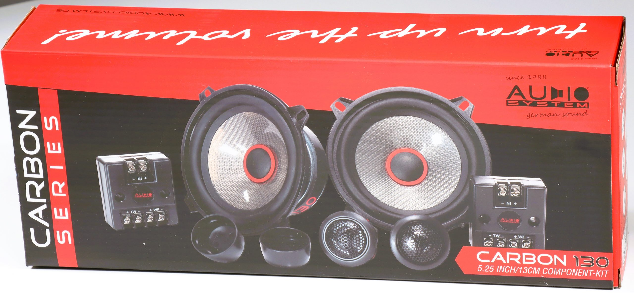 Schachtel mit Autolautsprechern, schwarz und rot. Lautsprecher, Hochtöner und Komponenten sind sichtbar. Text sagt Carbon Series und Audio System.