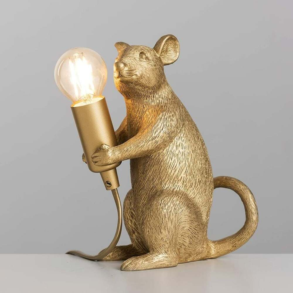 Eine goldene, mausförmige Lampe hält eine leuchtende Glühbirne. Die Maus sitzt aufrecht, der Schwanz ist gekrümmt. Der Hintergrund ist grau.