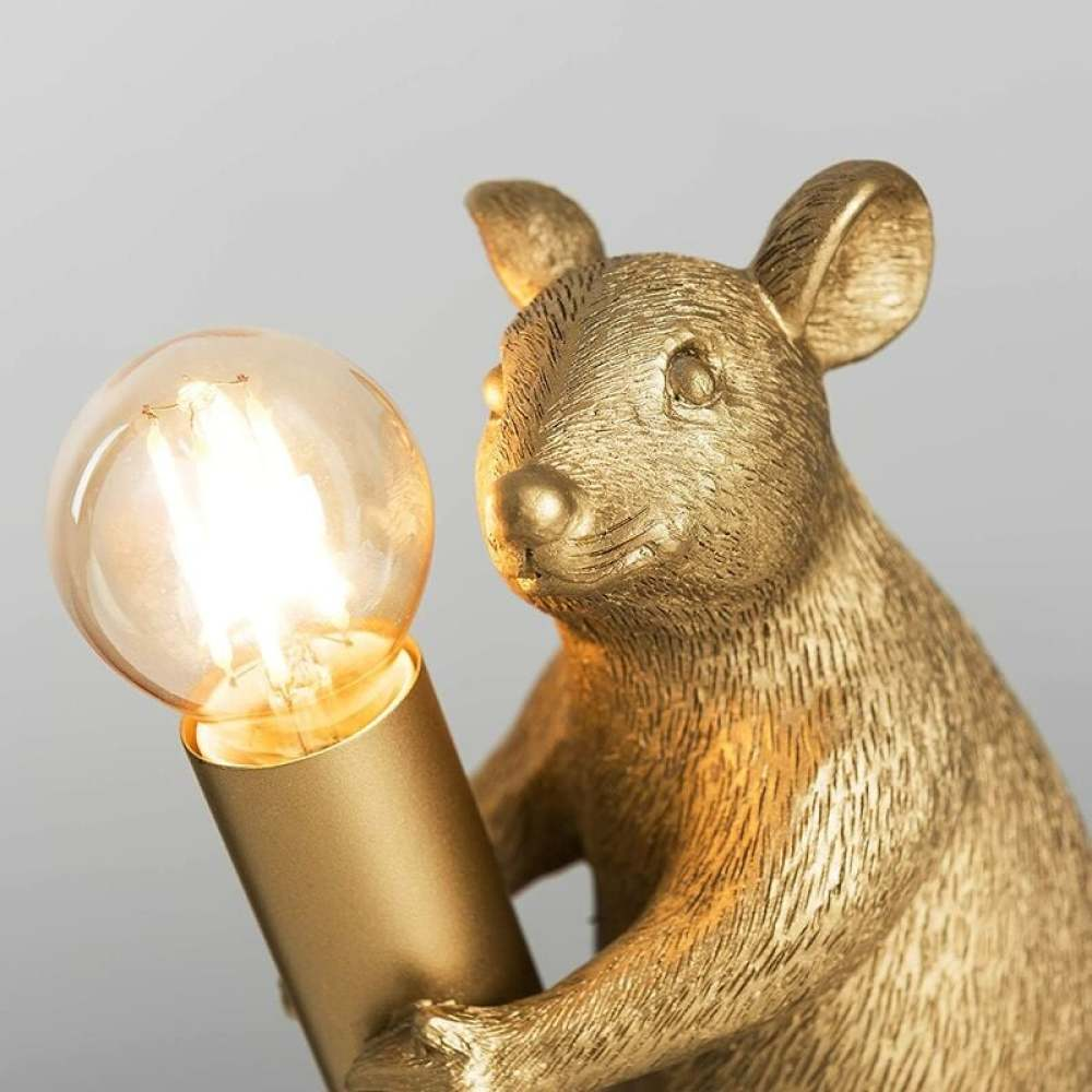Eine goldene Mäuse-Statue hält eine Glühbirne. Die Maus hat große Ohren und blickt zum Licht. Der Hintergrund ist schlicht.
