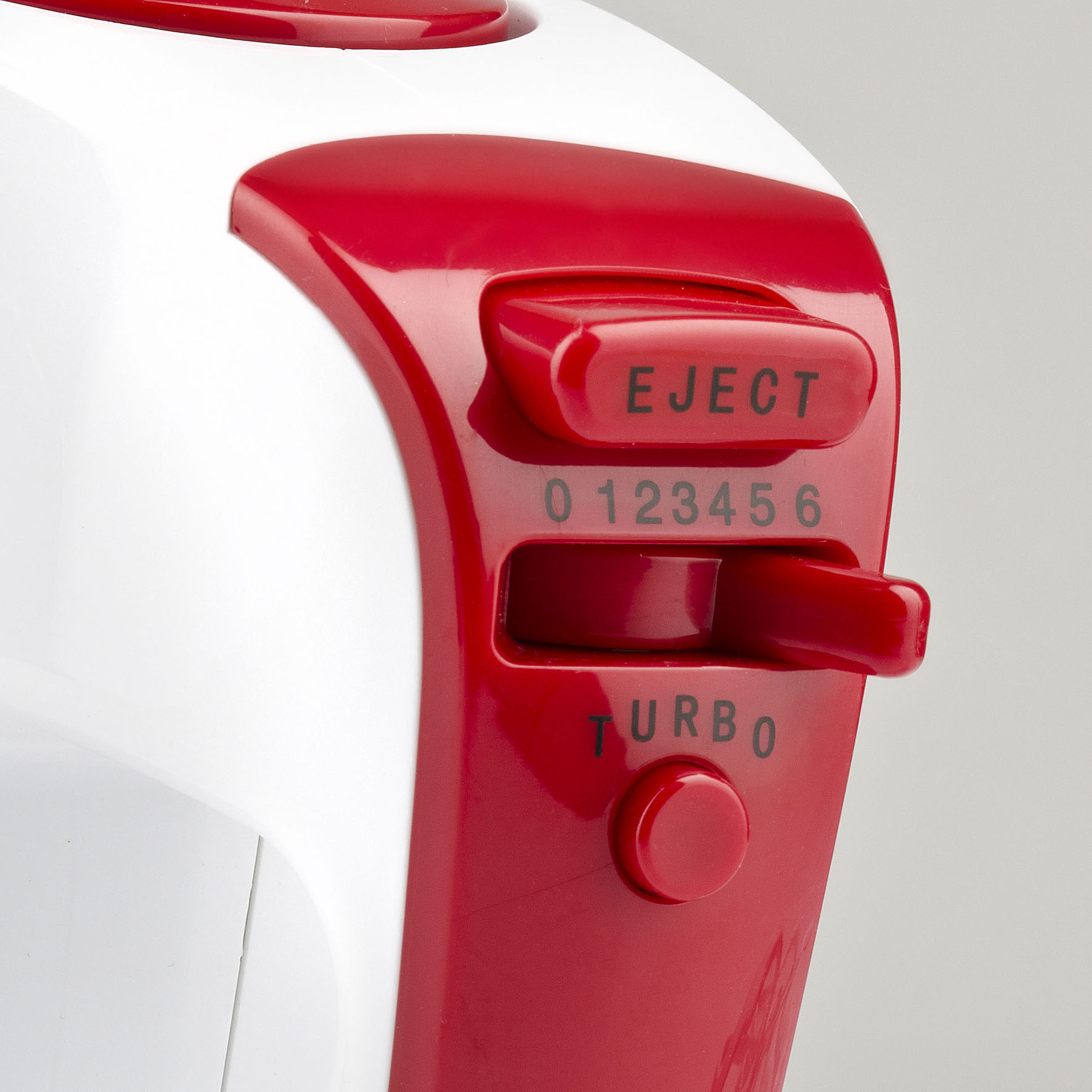 Zbliżenie czerwono-białego miksera ręcznego. Pokazuje ustawienia prędkości, przycisk turbo i przycisk wyrzutu.