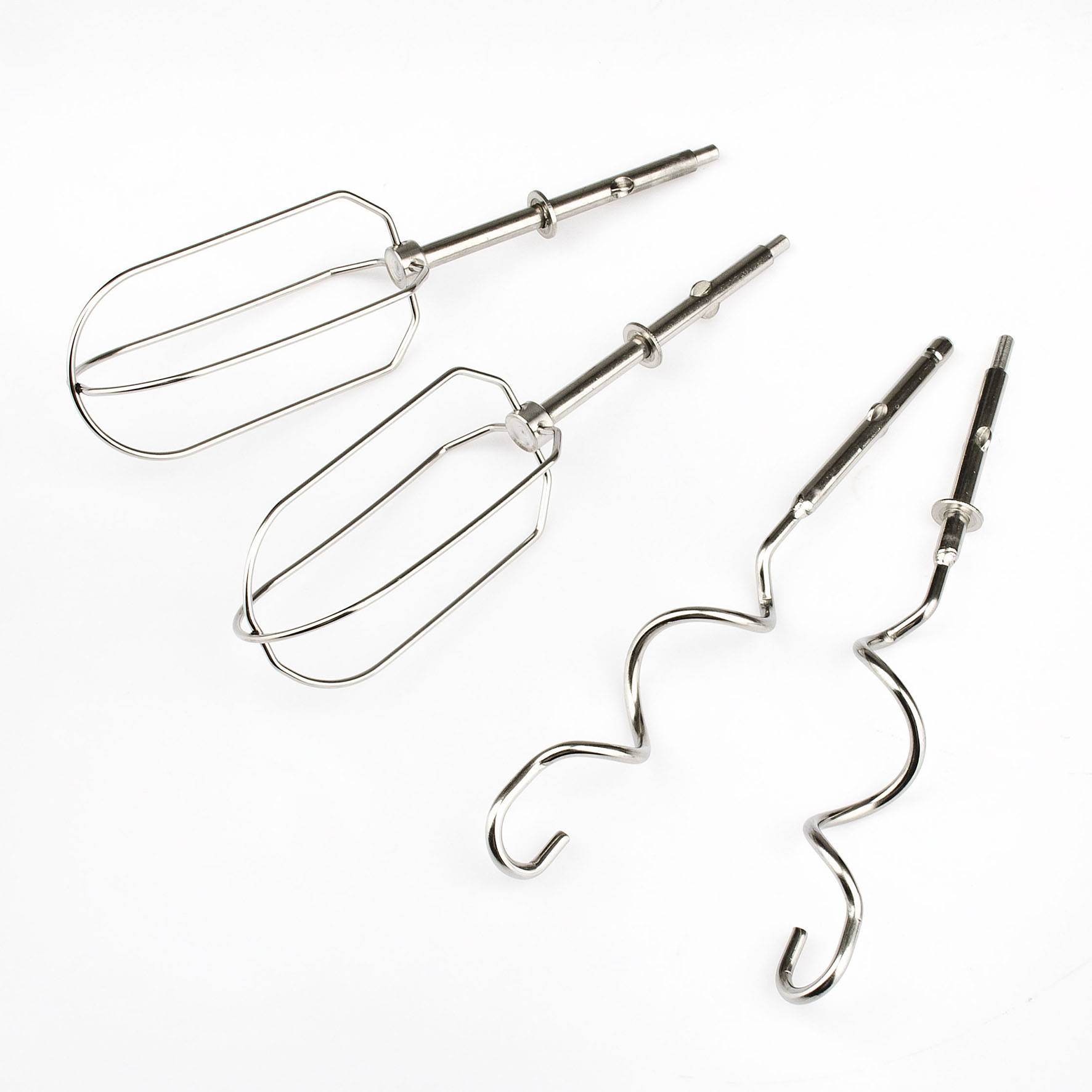 Cztery końcówki miksera ze stali nierdzewnej na białej powierzchni. Dwie w stylu trzepaczki, dwie w stylu haka do ciasta, wszystkie pod kątem.