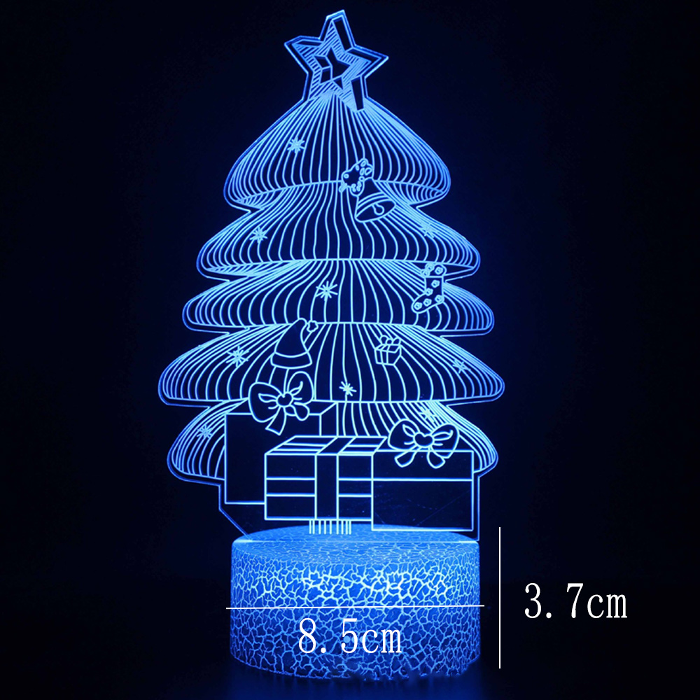 Eine blaue Weihnachtsbaum-förmige Lampe mit Geschenken, Stern, Glocke und Socken. Auf einem rissigen blauen Sockel vor schwarzem Hintergrund.