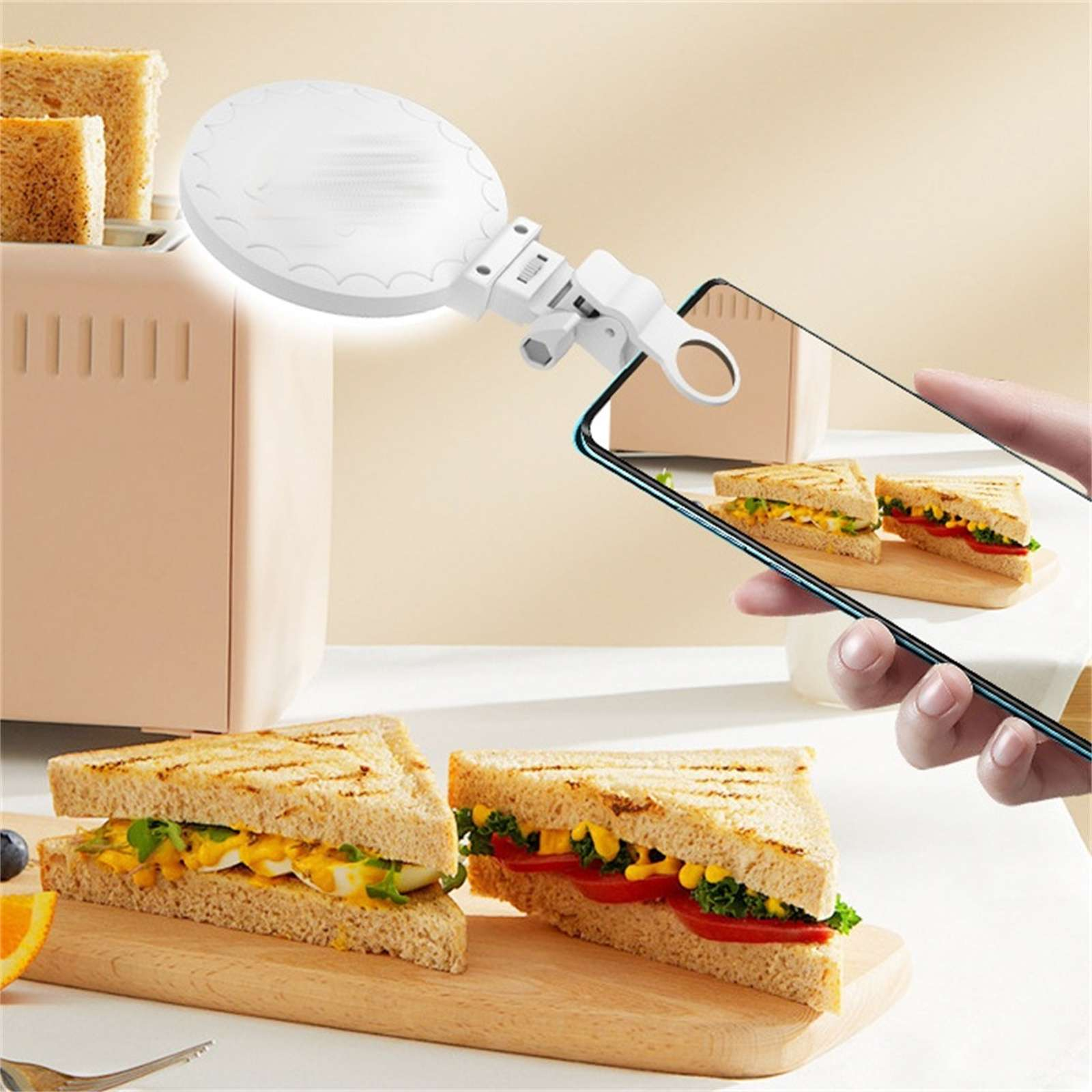 Eine Person fotografiert ein Sandwich mit einem Telefon. Zwei Sandwiches und ein Toaster sind sichtbar.