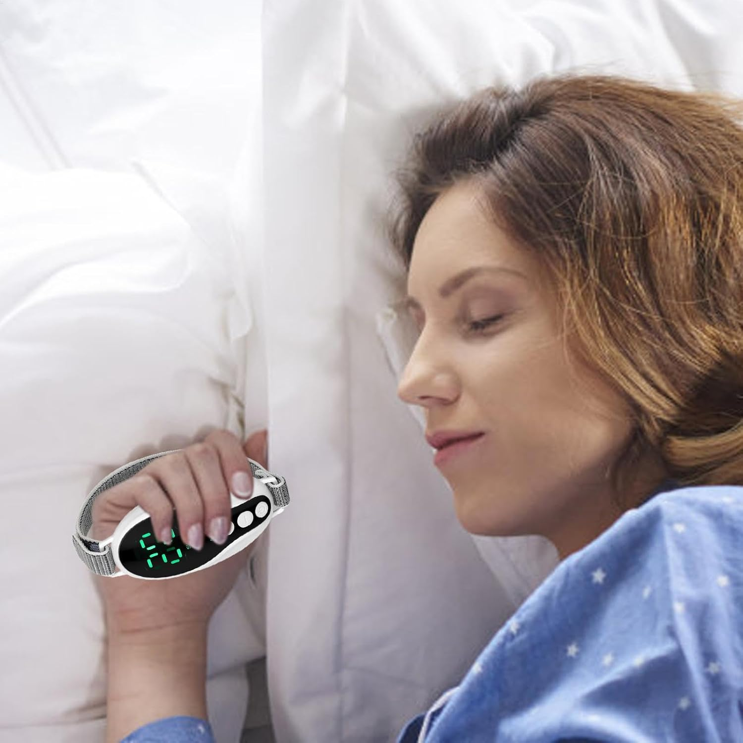 Frau im Bett hält einen Schlaftracker. Sie trägt einen blauen Pyjama. Der Tracker zeigt grüne Zahlen. Weißes Kissen im Hintergrund.