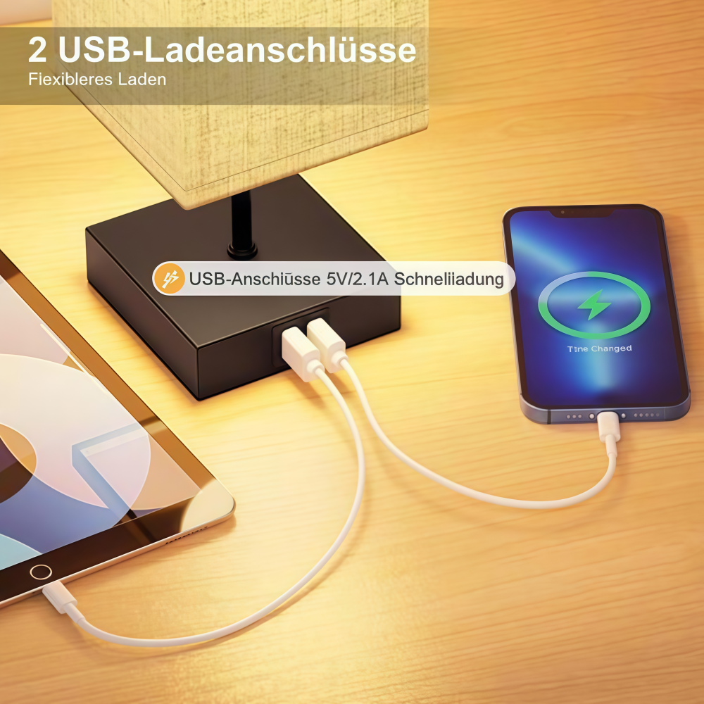Ein Telefon, das geladen wird, ein Tablet und eine Lampe mit USB-Anschlüssen auf einer Holzoberfläche.