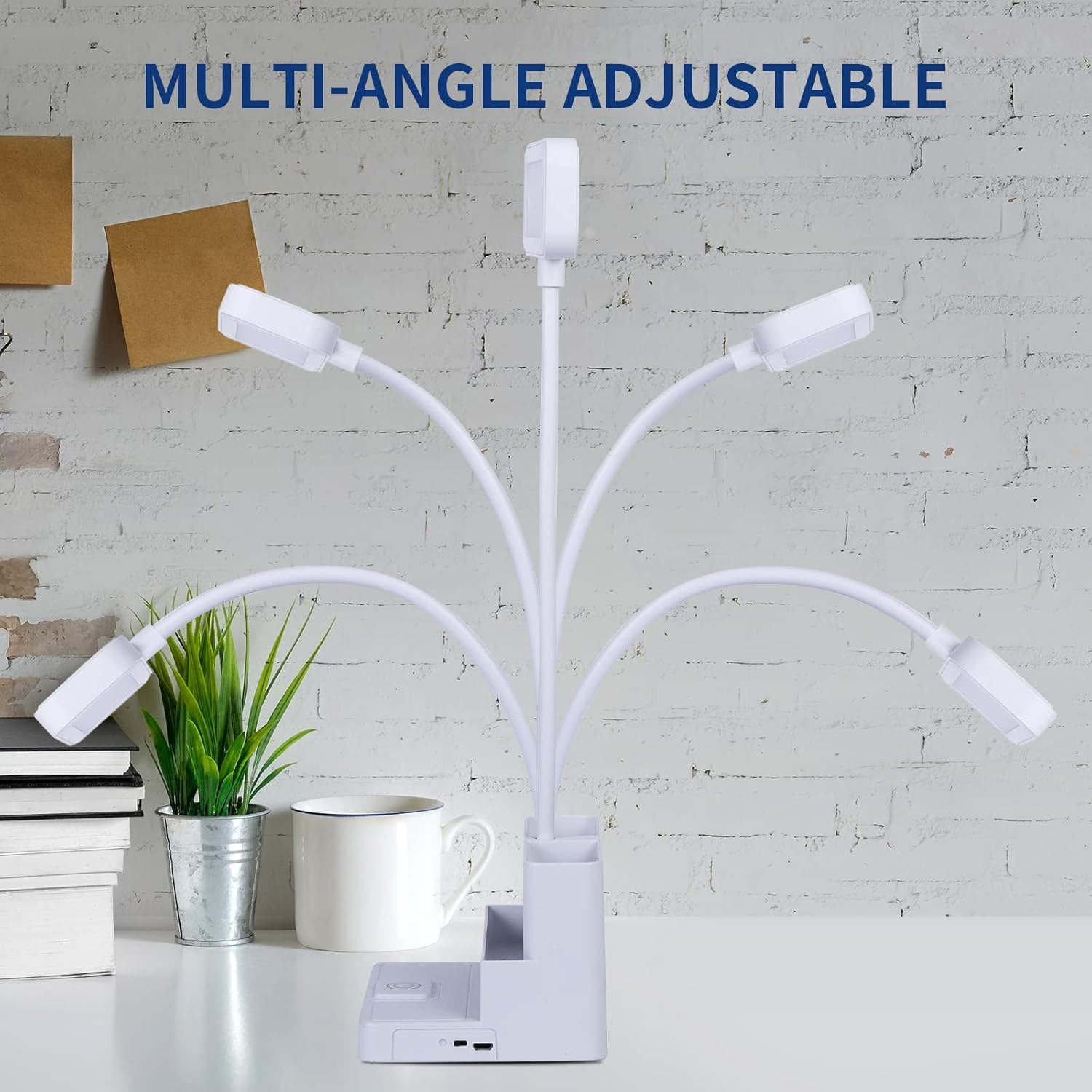 Eine weiße, multiwinkelverstellbare Lampe mit mehreren Lichtern. Auf dem Tisch stehen eine Pflanze, Bücher und eine Tasse. Der Hintergrund ist eine weiße Ziegelmauer.
