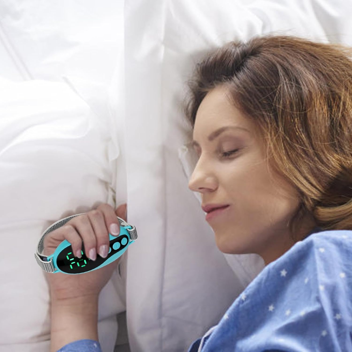 Eine Frau liegt im Bett und hält einen Schlafüberwachungsmonitor. Der Monitor ist türkis mit digitaler Anzeige. Die Frau trägt einen blauen Pyjama.