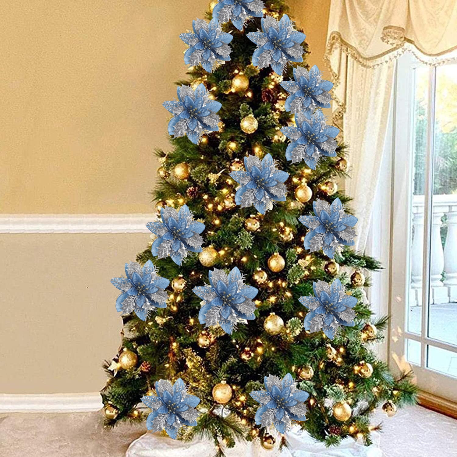 Ein geschmückter Weihnachtsbaum mit blau-silbernen Blumenornamenten. Der Baum ist mit goldenen Lichtern beleuchtet, vor einem Fenster.