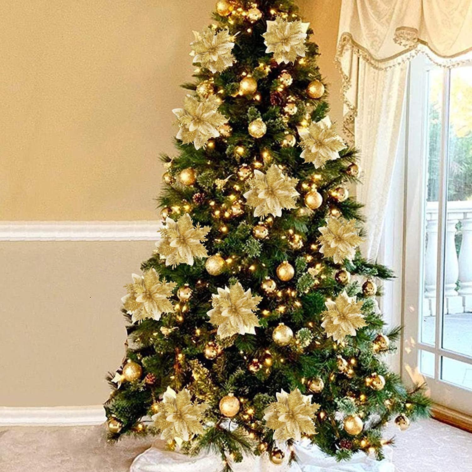 Ein geschmückter Weihnachtsbaum mit goldenen Ornamenten und Blumen. Er steht in der Nähe eines Fensters mit weißen Vorhängen, in einem Raum.