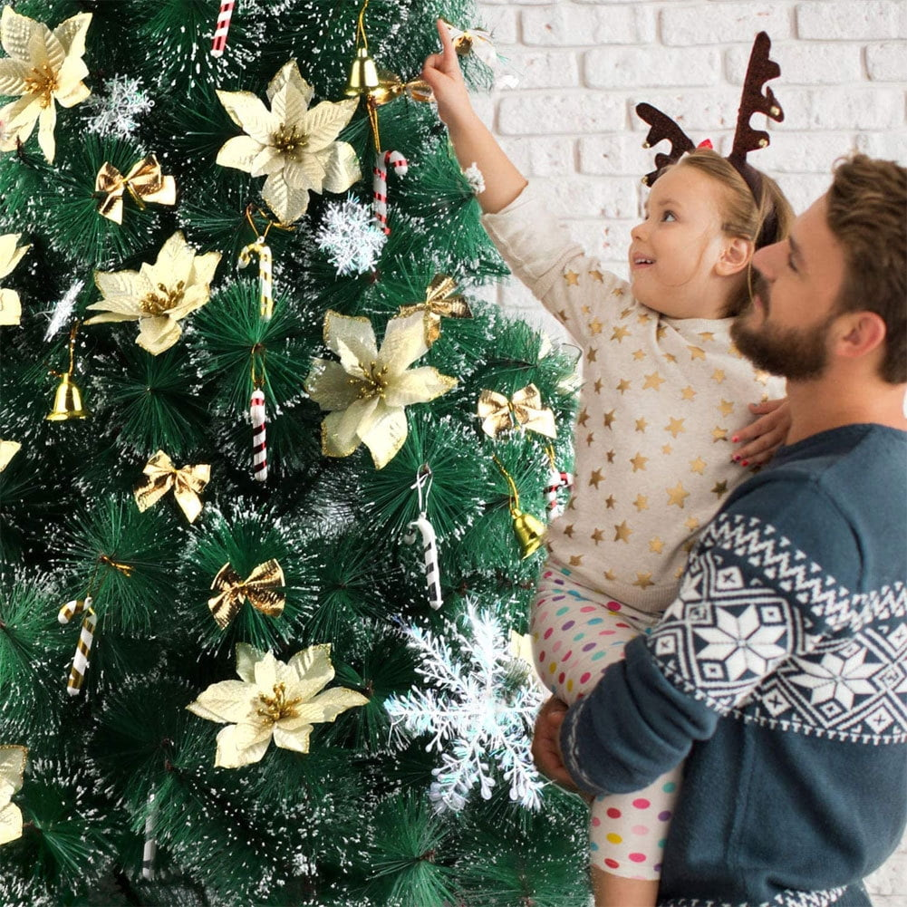 Ein Mann hält ein Mädchen mit Rentiergeweih. Sie schmücken einen Weihnachtsbaum mit goldenen Ornamenten und Zuckerstangen.