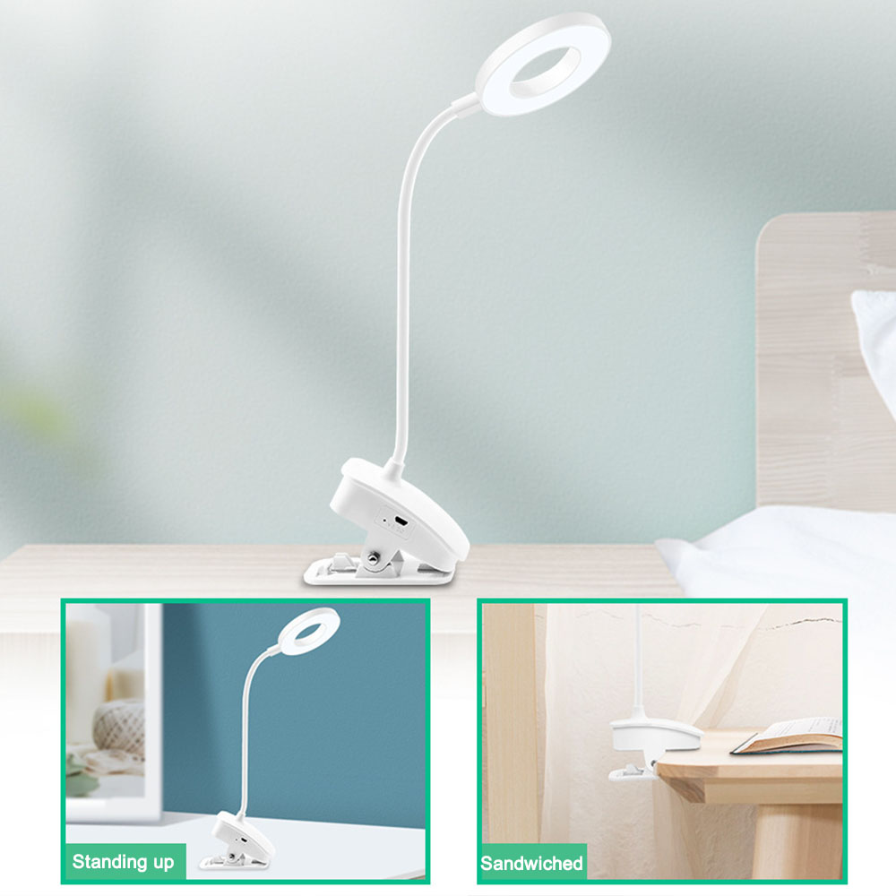 Weiße Schreibtischlampe mit Ringlicht, an einer Oberfläche befestigt. Der Hintergrund zeigt eine hellblaue Wand, ein Bett und zwei kleinere Bilder.