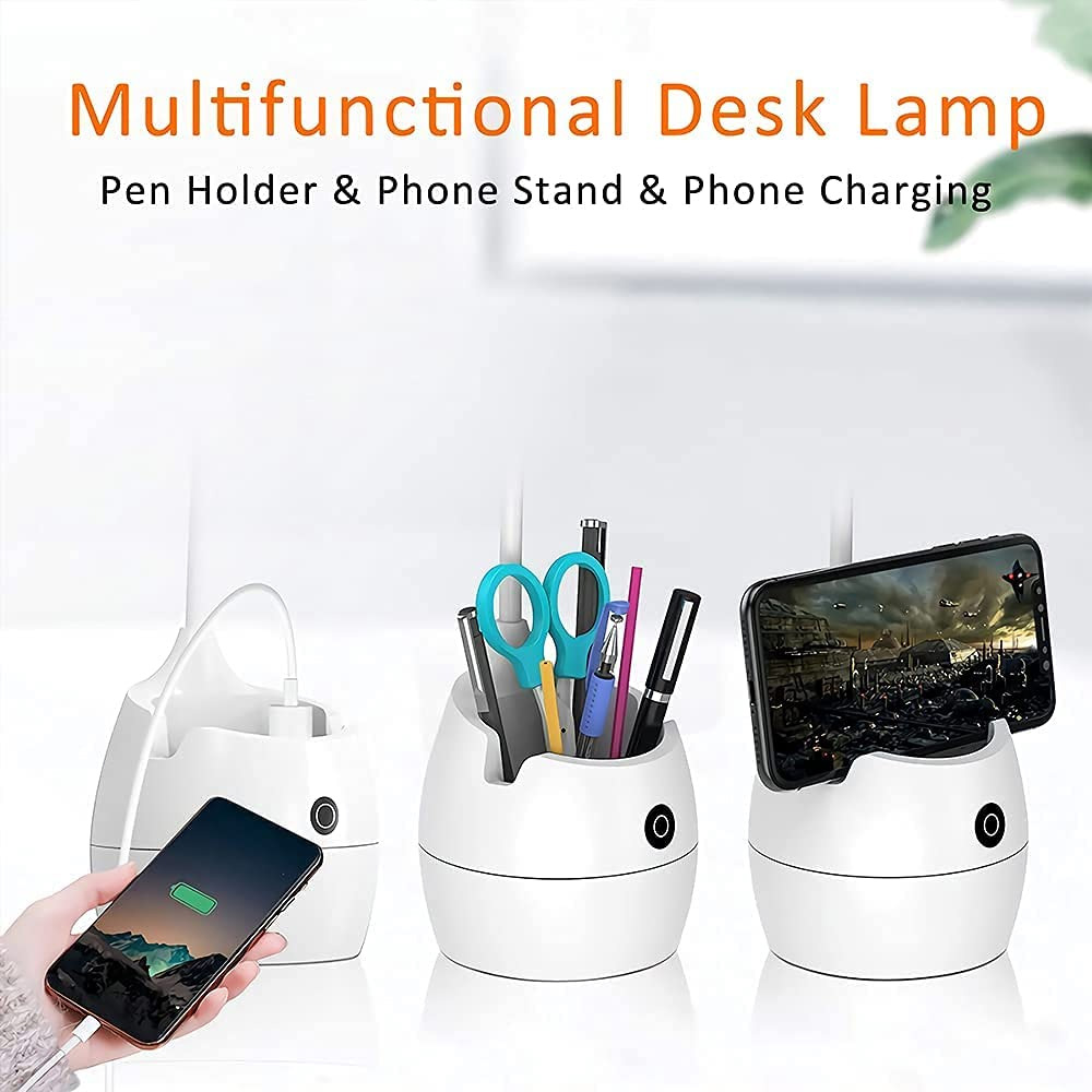 Weiße Schreibtischlampe mit Stifthalter, Telefonständer und Lademöglichkeit. Eine Hand hält ein Telefon. Stifte, Scheren und ein Telefon befinden sich in den Haltern.